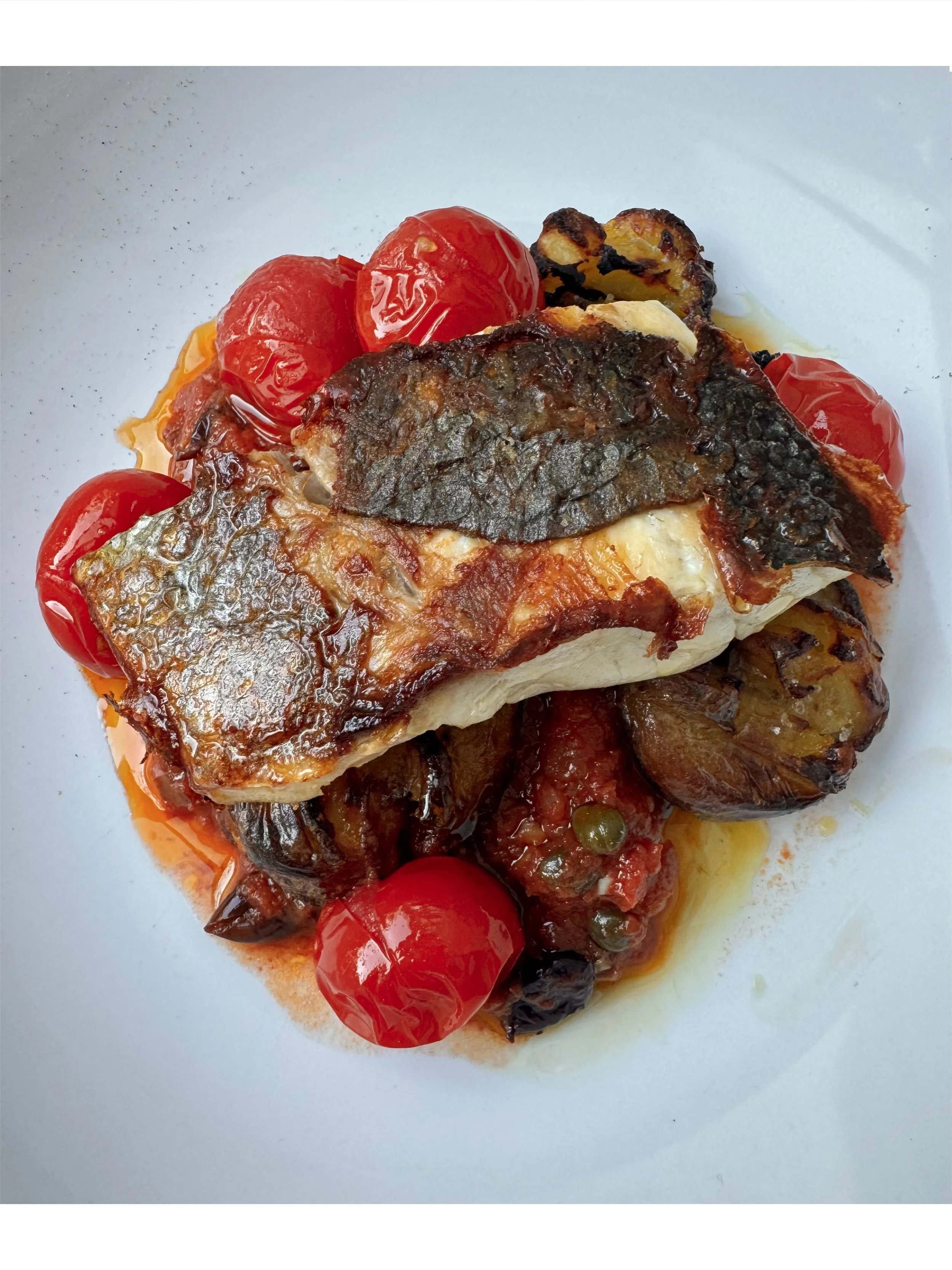 Pan-seared fish with seasonal vegetables and slow-roasted tomatoes from Chef Adrienne’s private dining menu.