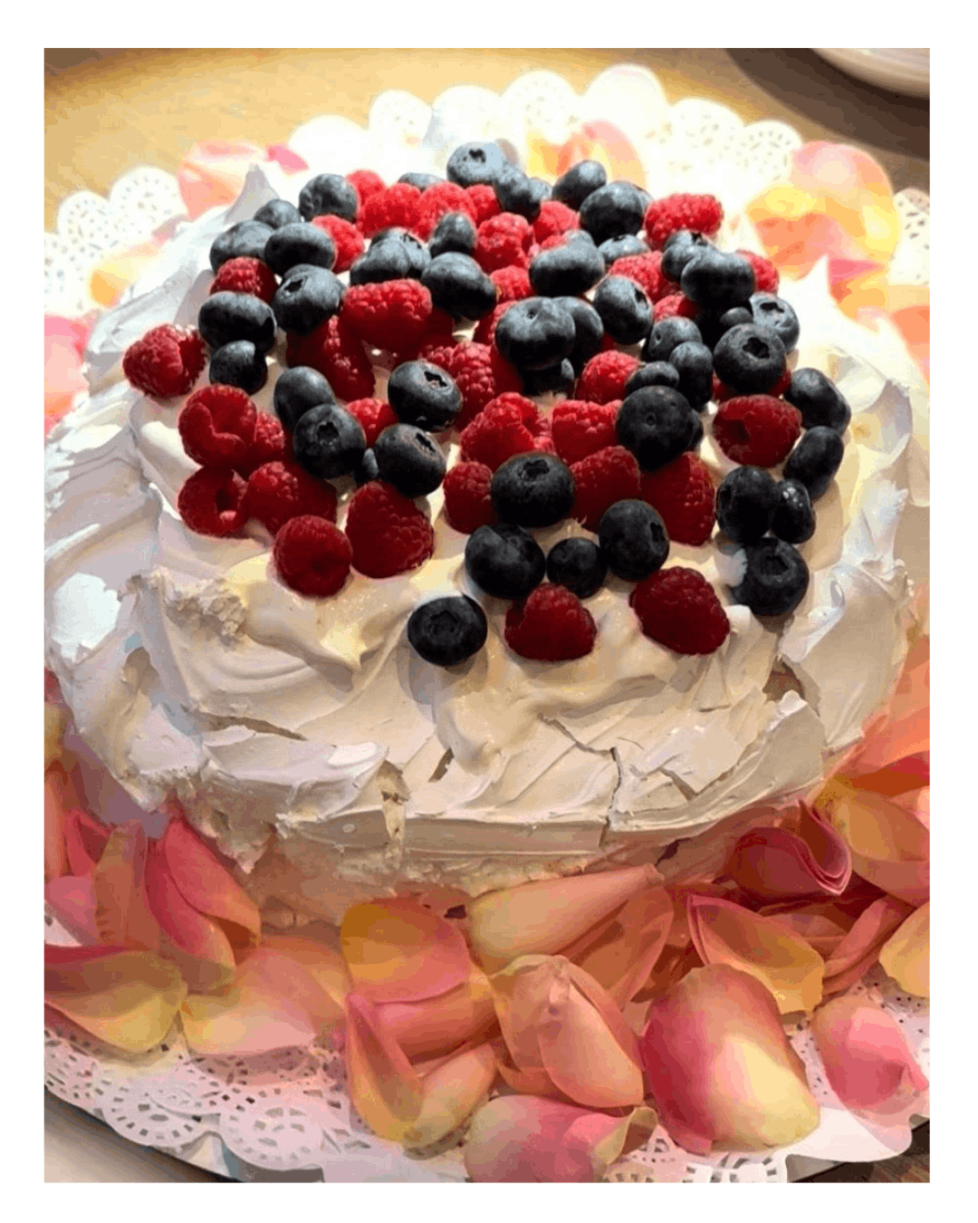 Berry pavlova with fresh raspberries and blueberries served during a private dining experience in Amsterdam by Chef Adrienne, featuring crisp meringue and whipped cream.