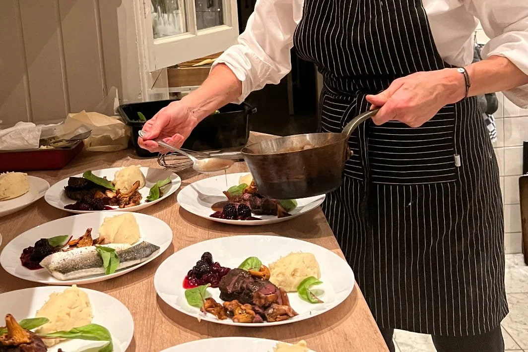 Chef Adrienne plating seasonal main courses in her home kitchen for an intimate private dining menu in Amsterdam.