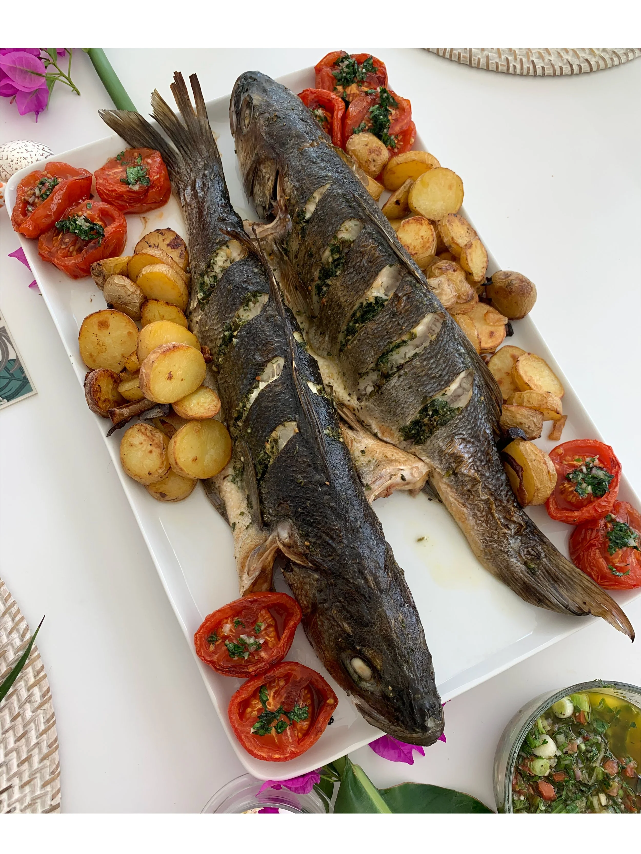 Whole roasted fish served with seasonal potatoes and tomatoes for a shared private dining experience in Amsterdam.