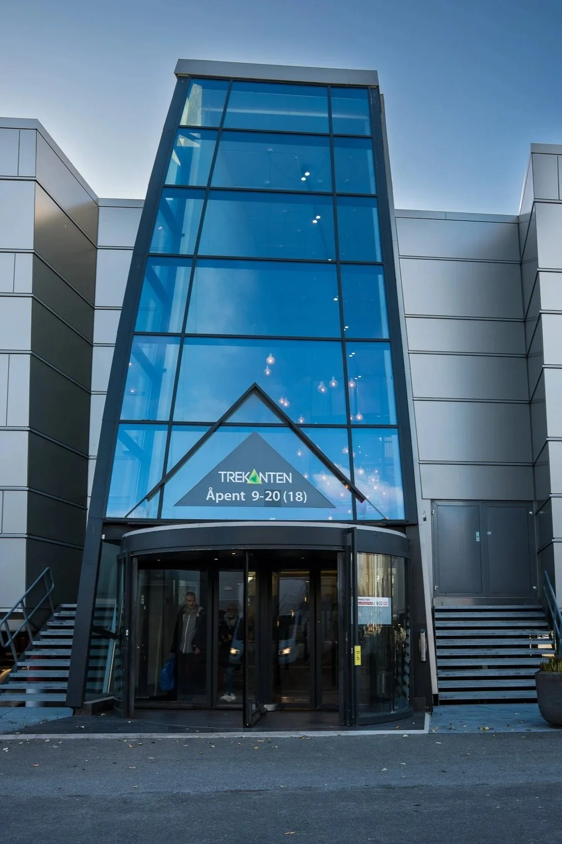 Utsiden av en butikk med inngang bygd av glass, som heter Treetanten. Åpningstidene er 9-20, med stengt på søndag.