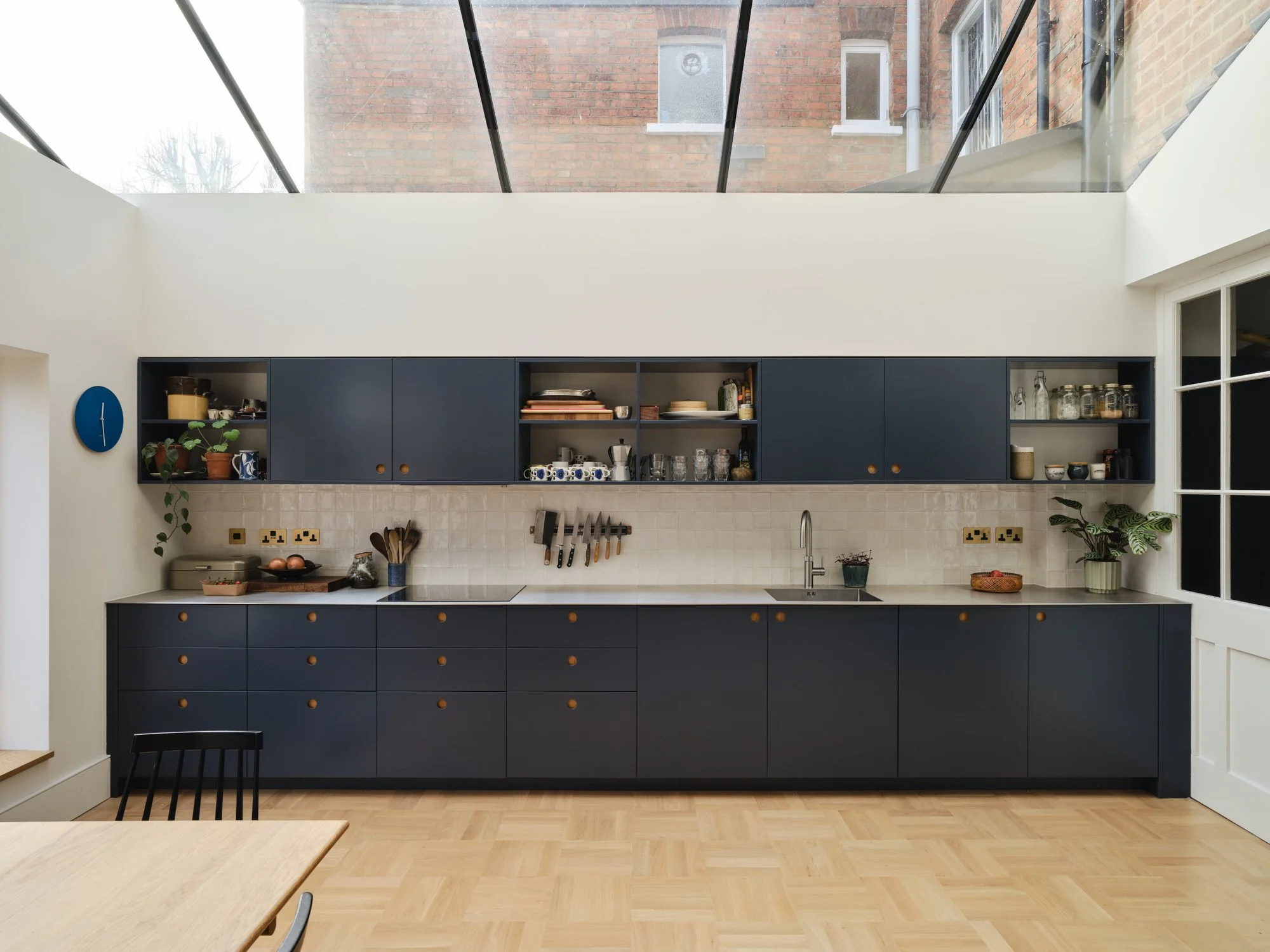Basketweave parquet flooring, navy Scandinavian kitchen, slimline framed rooflight flooding the kitchen with natural light
