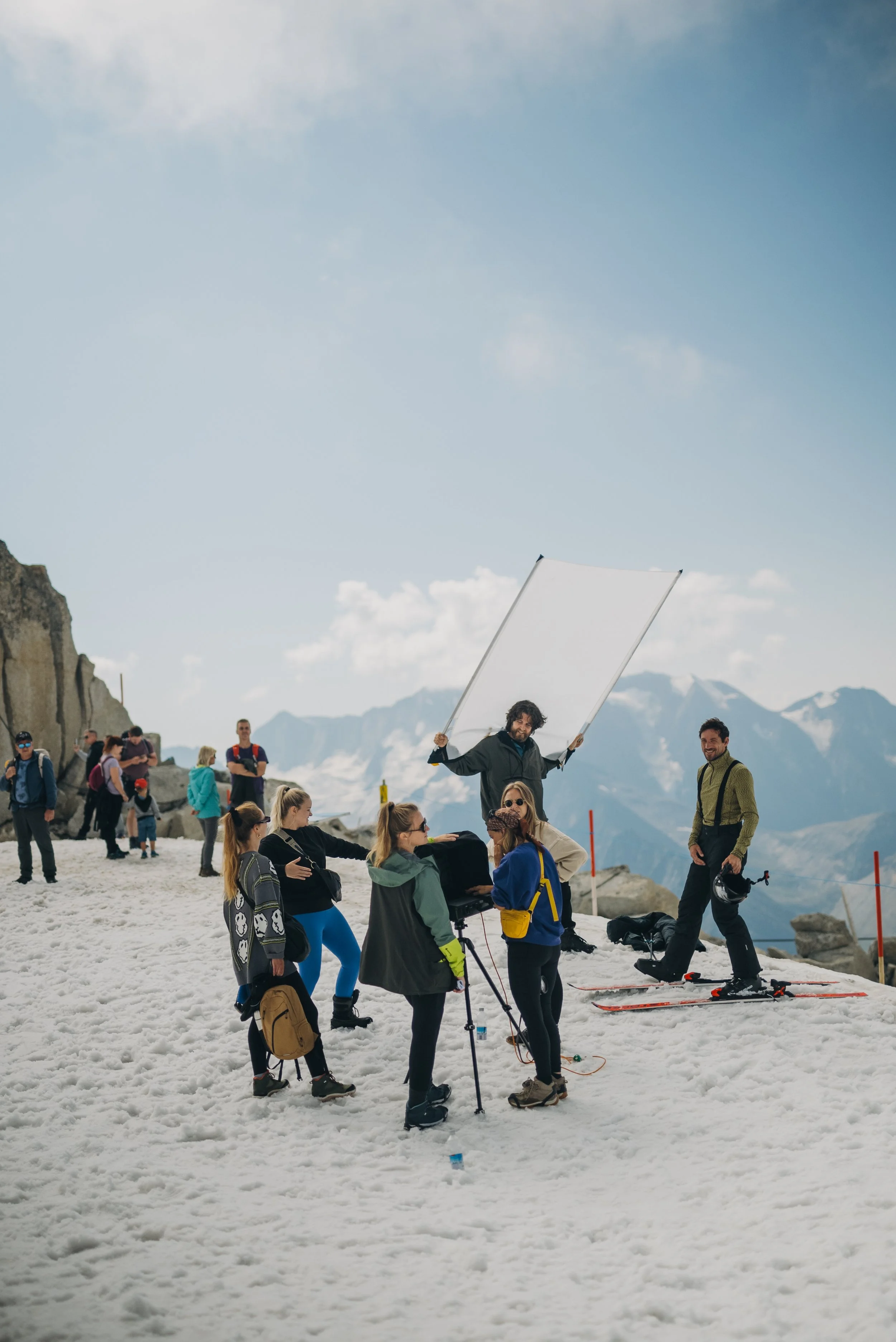 Filmmakers maken een opnames op een besneeuwde berg met een bergachtig landschap op de achtergrond.