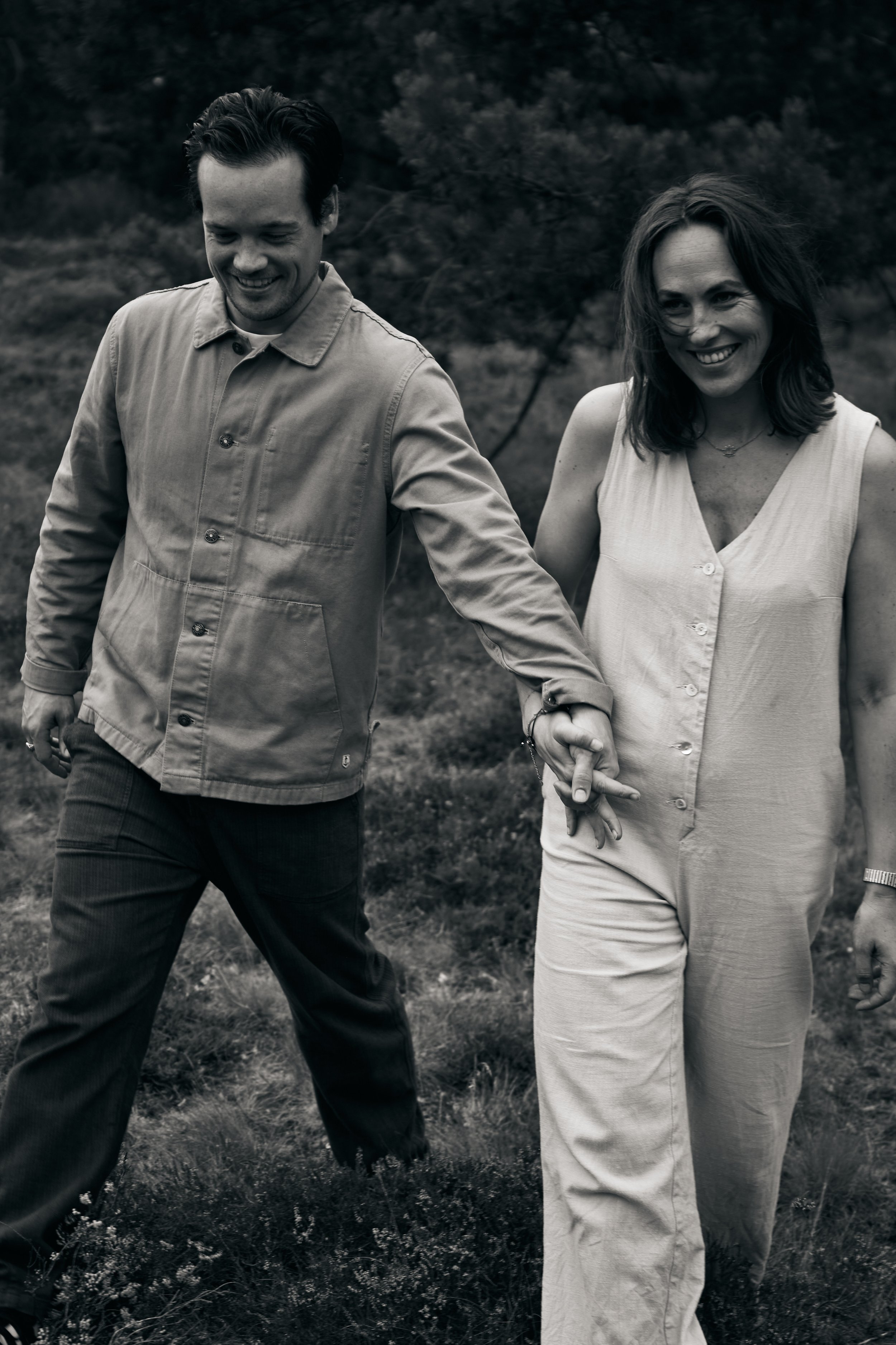 Twee mensen wandelen samen in een park, hand in hand, en lachen.