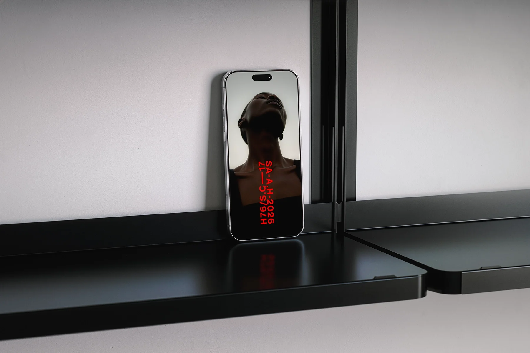 A smartphone resting on a black surface captures a person's reflection with their head tilted back, showing only silhouette and low lighting, with red digital text overlay that reads 'SA-AH-2026, 17-S-29/92H.'