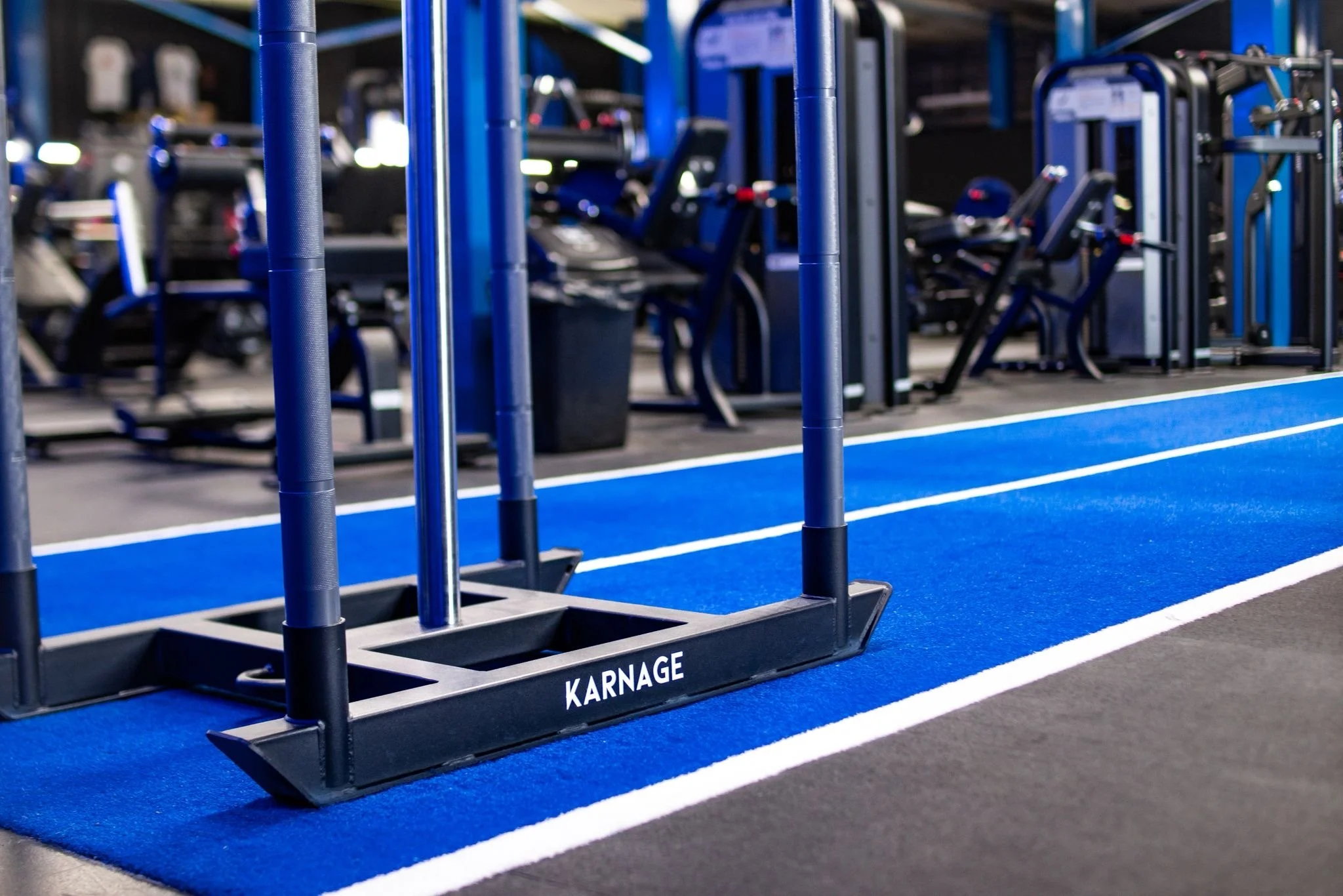 Blue gymnasium with exercise equipment, sled and a blue running track.
