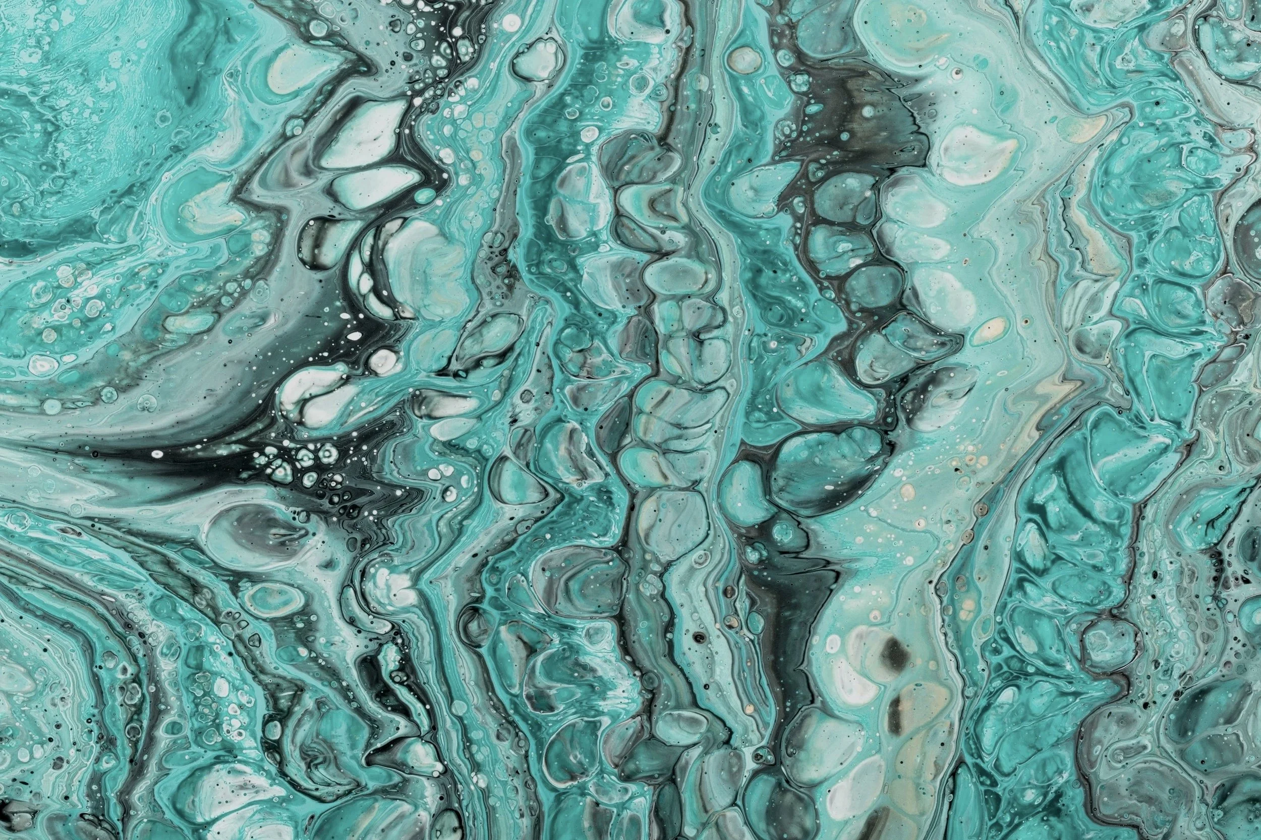 Close-up of swirling teal, black, and white paint creating an abstract, marbled pattern.