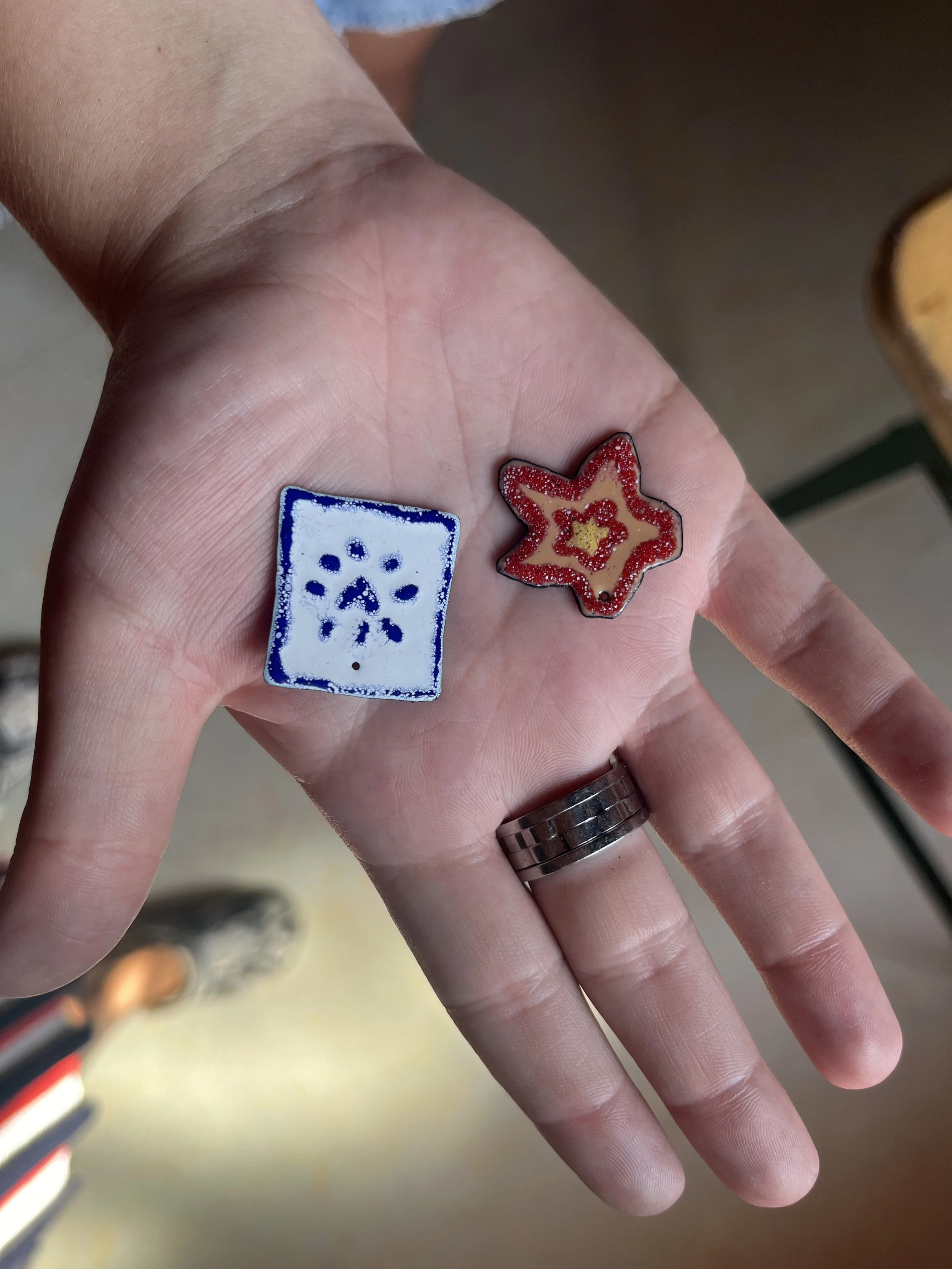 Hånd med to små sav dit eget design vedhæng - stjerne og blå og hvid mønstret firkant.
