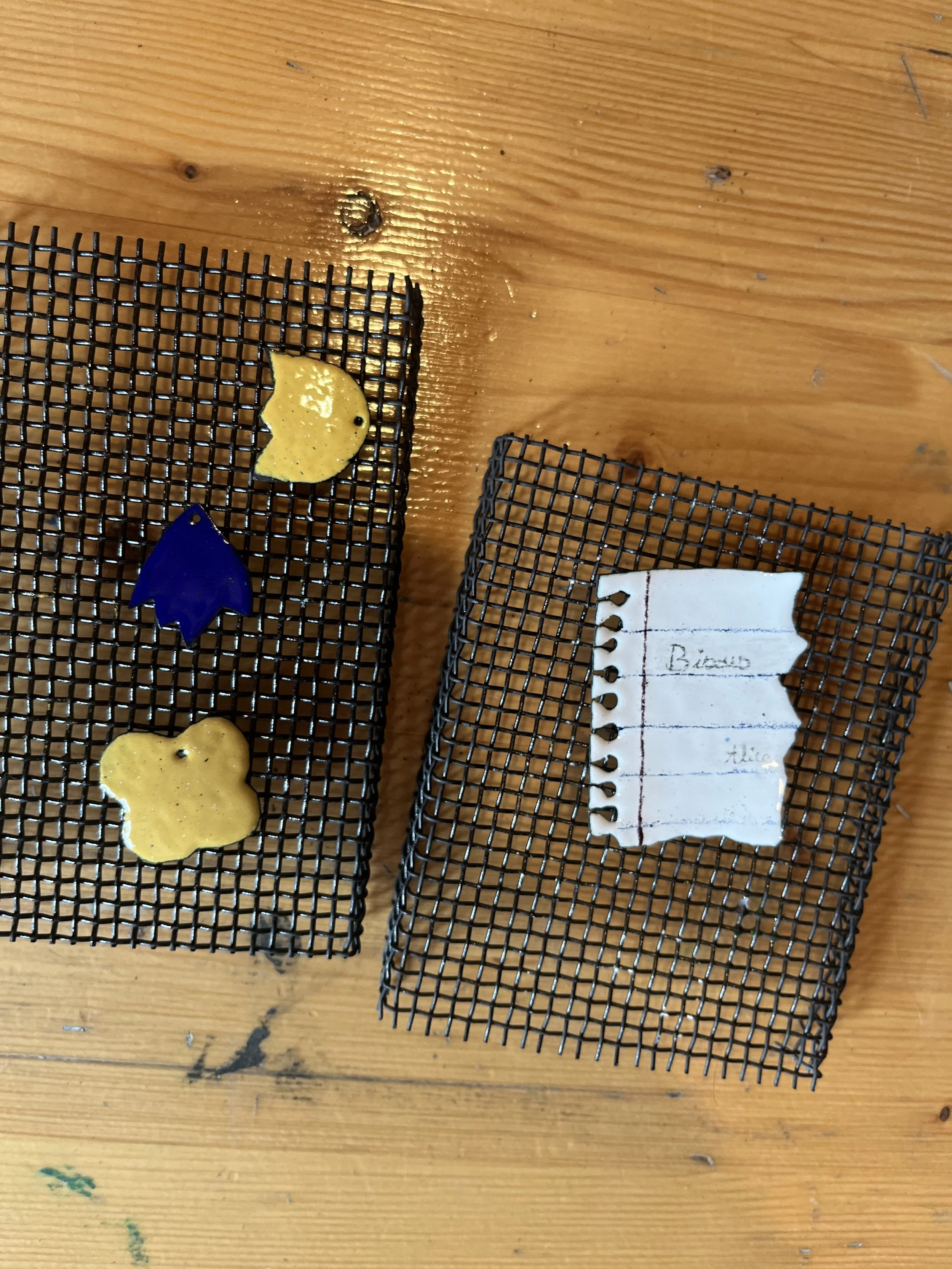 To sorte plastikkurve med tre tatoveringer af forskellige figurer og en notesblok med navn skrevet på.