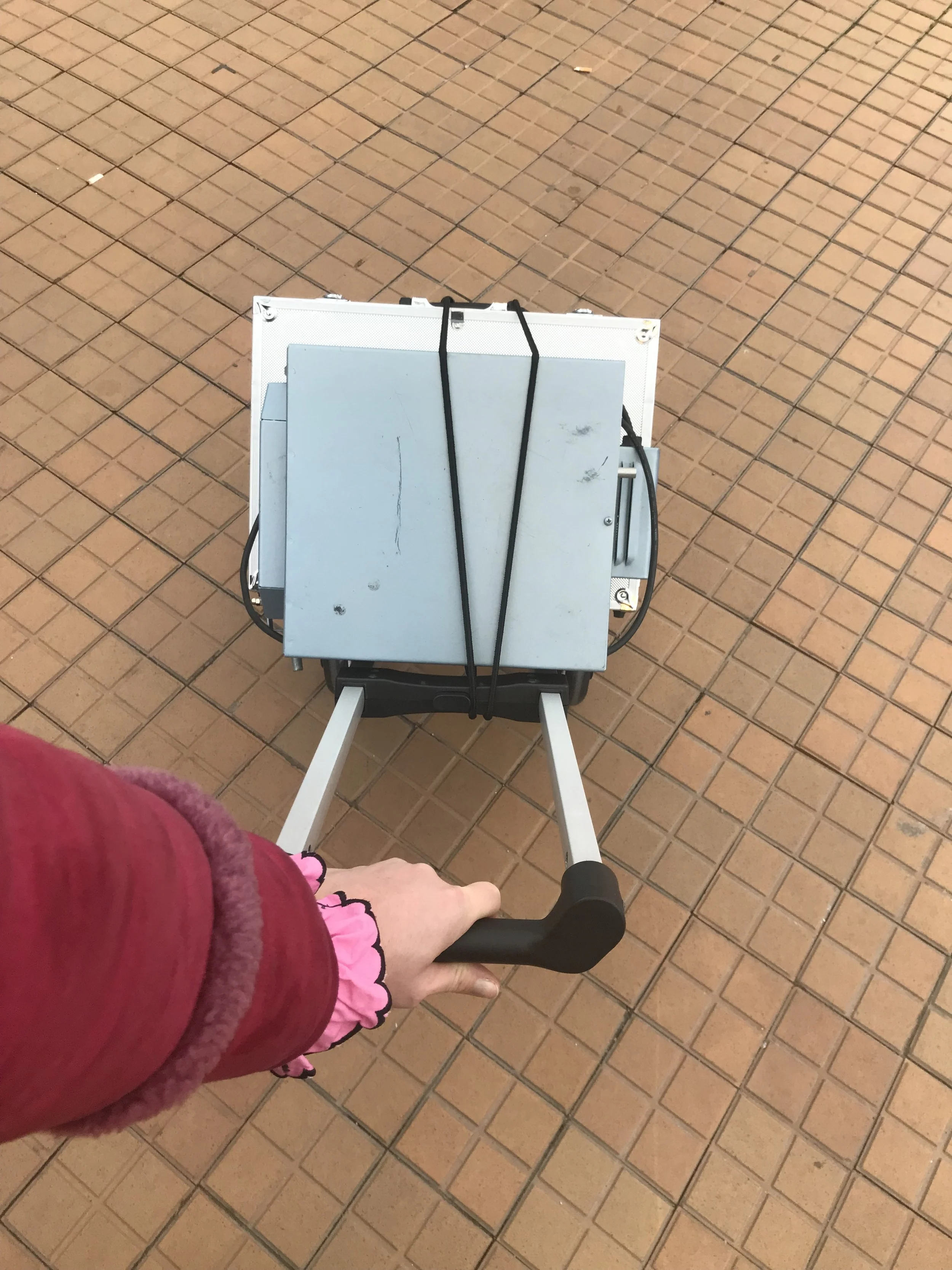 Person holder sækkevogn, hvor der står stablet to værkstedskufferter over øverst den lille blå emaljeovn.