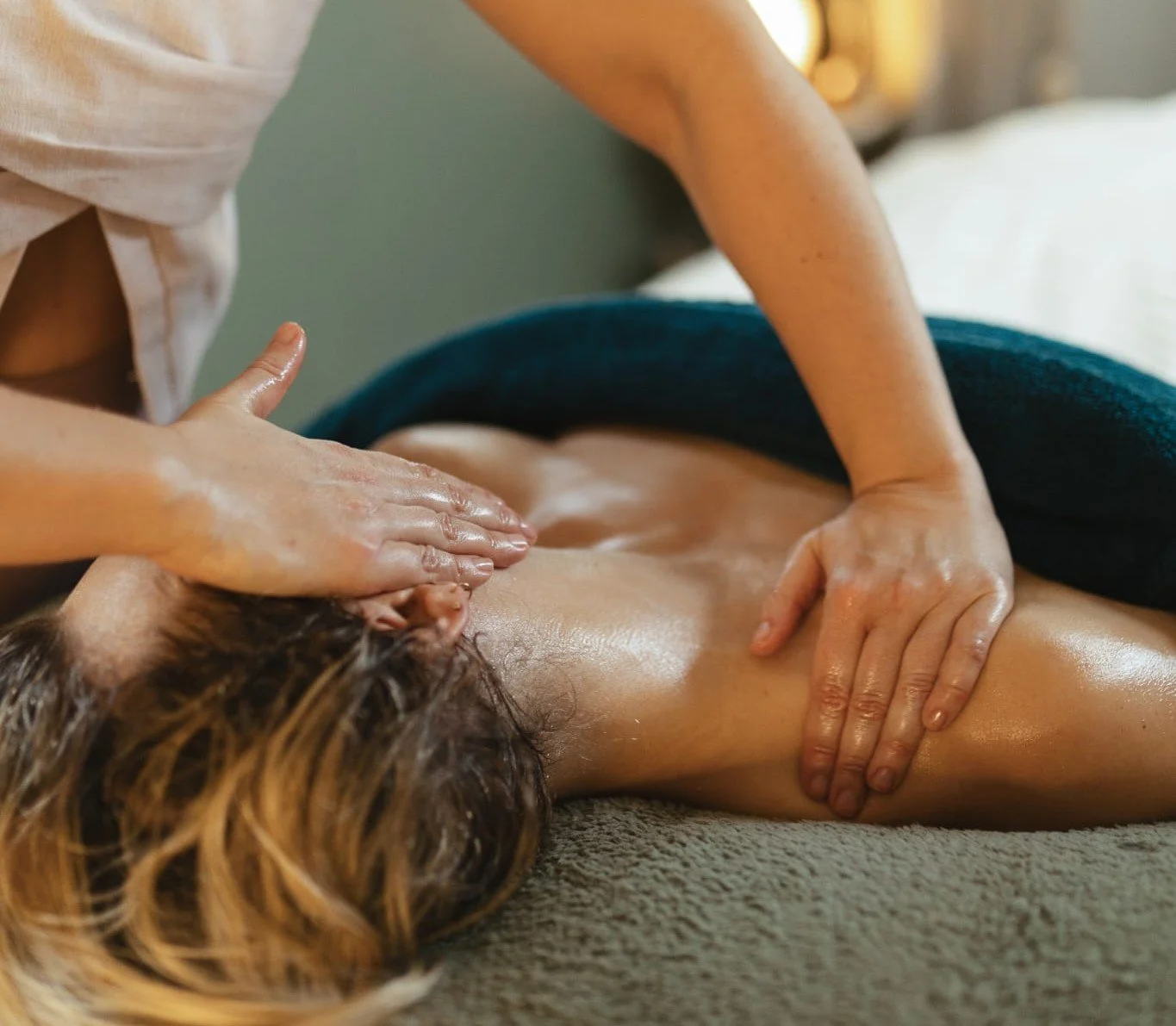Person receiving a massage on their back from a massage therapist in a spa setting.