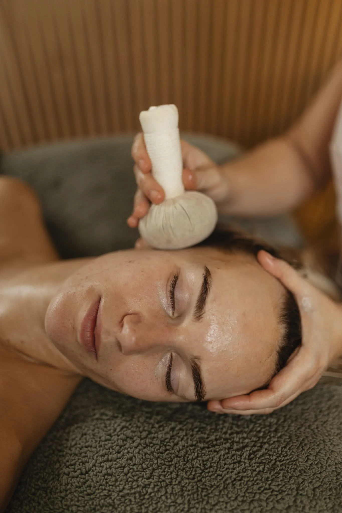 A lady having her face massaged with a hot herbal compress.