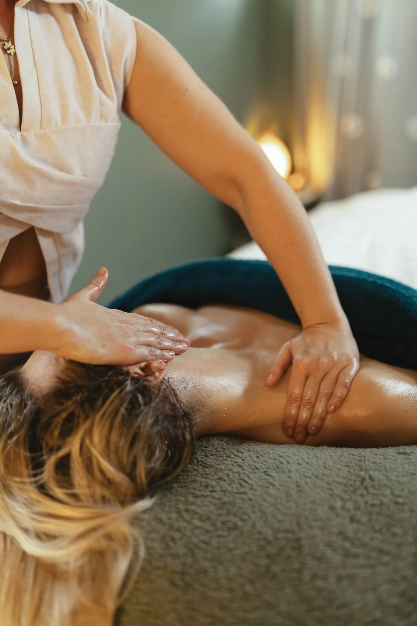 A person receiving a massage while lying face down on a massage table, with a massage therapist applying pressure with their hands.
