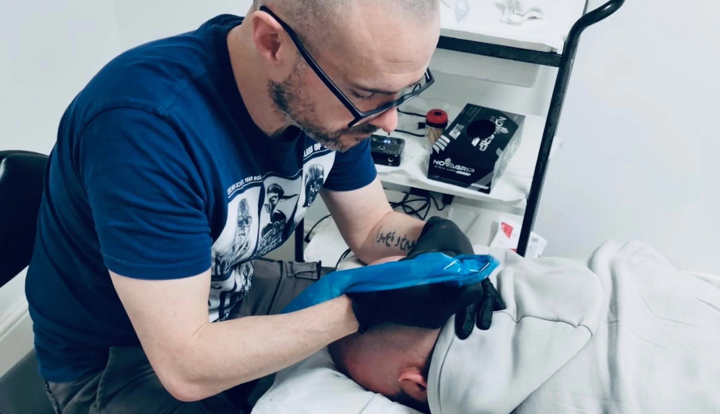 Wearing nitrile black gloves, Patrick Marshall performs a scalp micropigmentation procedure on a client.