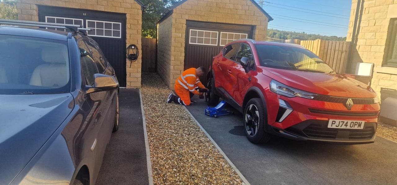 Technician providing emergency mobile tyre fitting on drive.