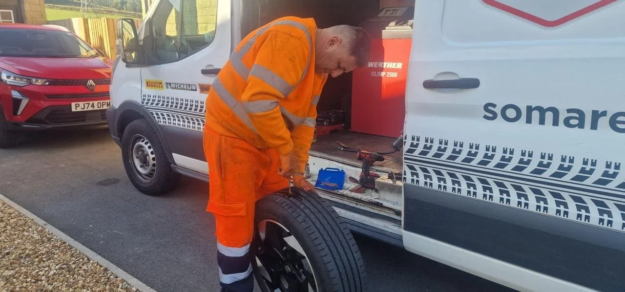 Mechanic performing a mobile puncture repair for a customer at home.