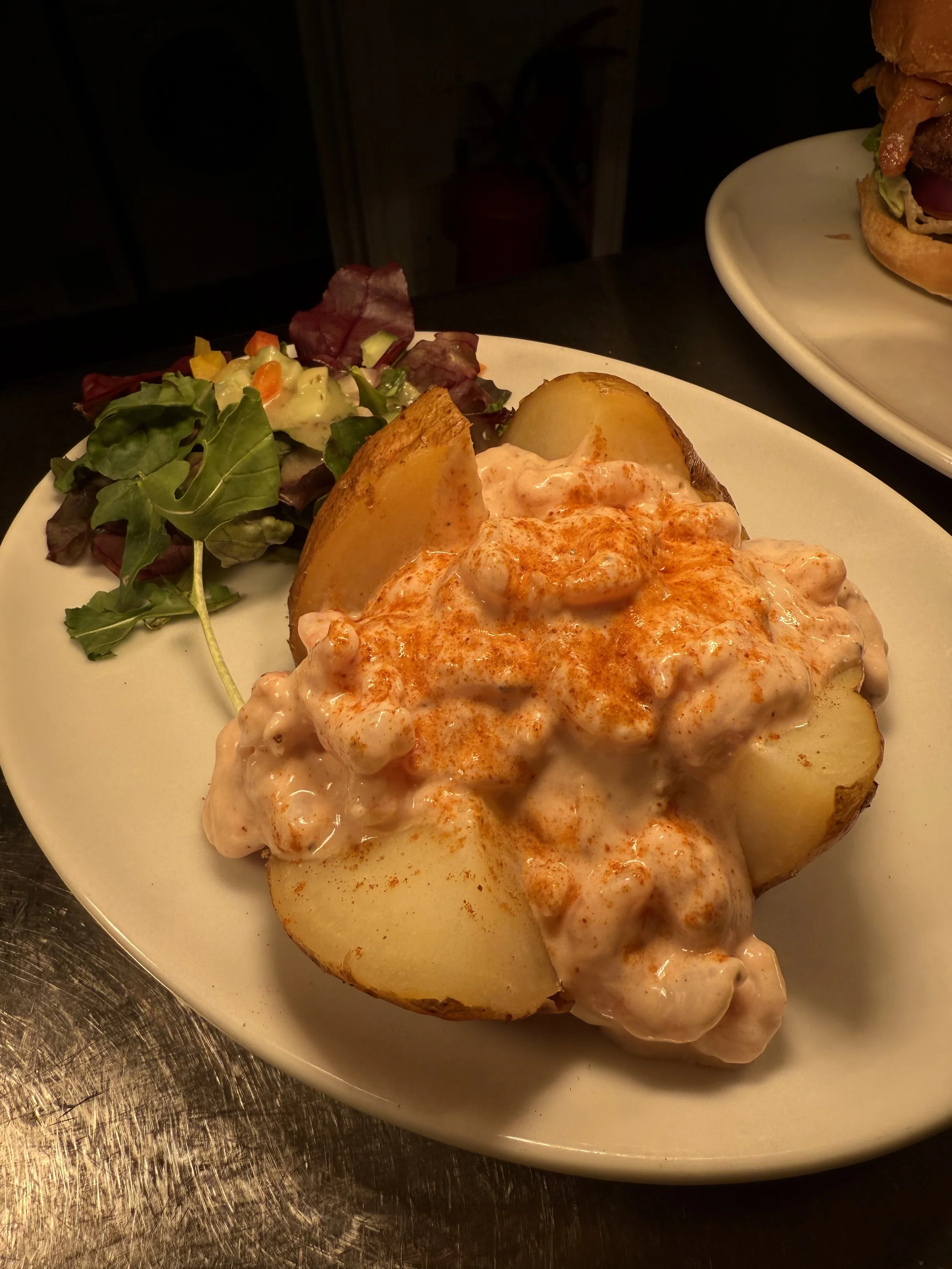 Baked potato topped with sour cream and paprika, served with a side salad of mixed greens.