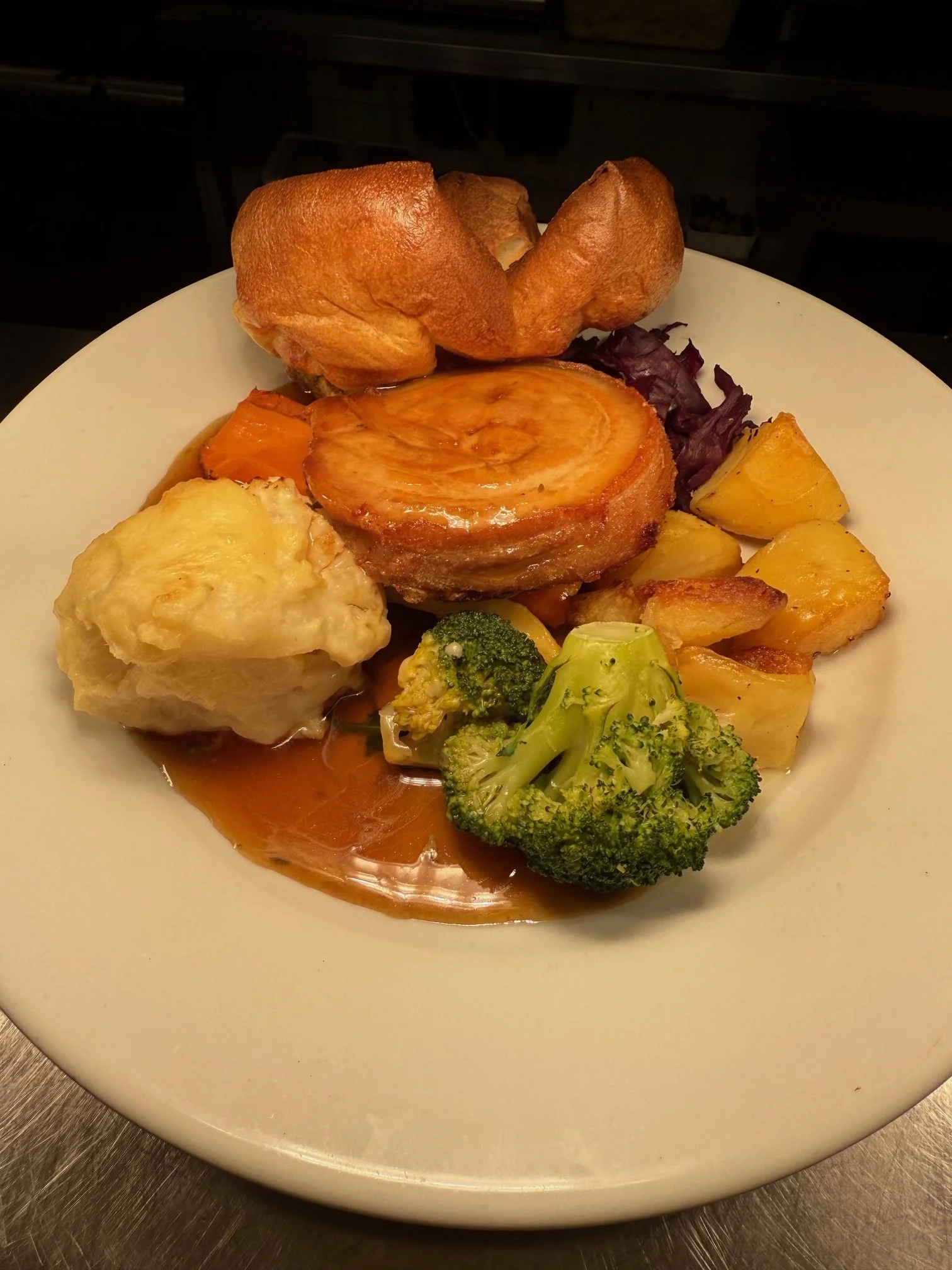 Sunday menu. Plate with baked potato, broccoli, roasted potatoes, a pie, mashed potatoes, a Yorkshire pudding, and some gravy - based in The Queen Inn, dummer 