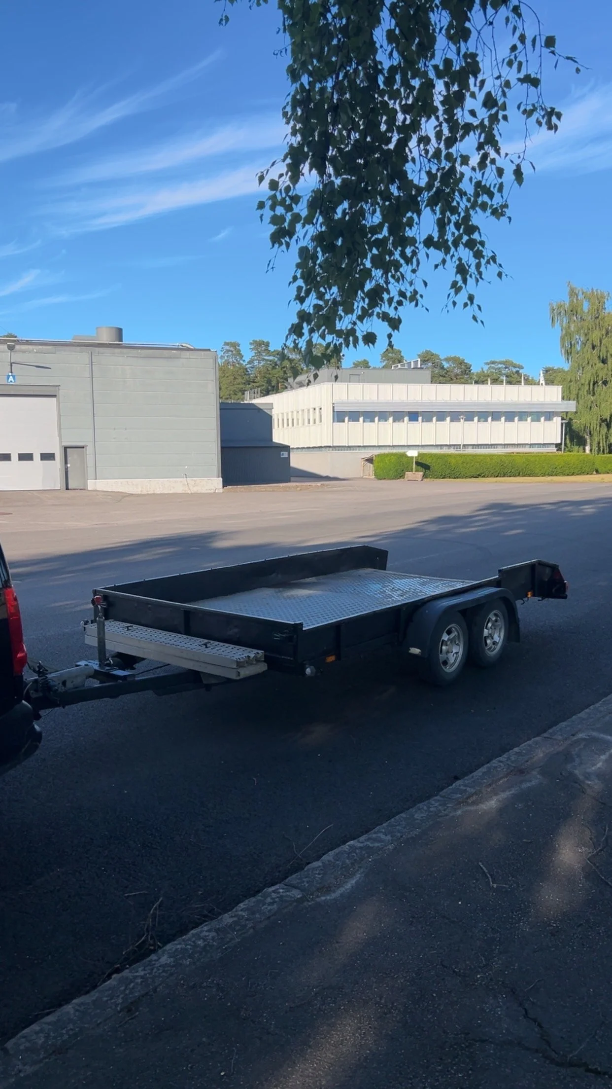 En tom flak med dubbla hjul placerad på en asfaltsparkering.