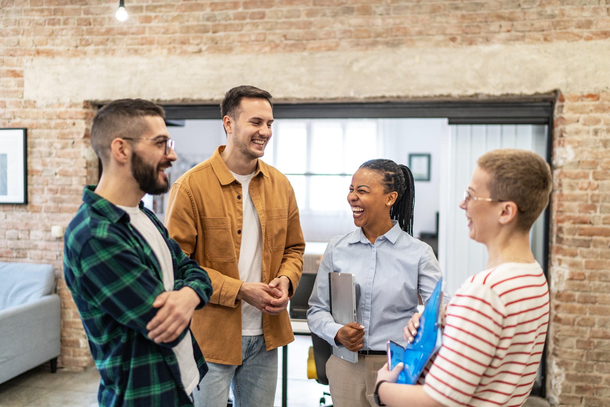 Group of adults chatting and laughing in an office environment