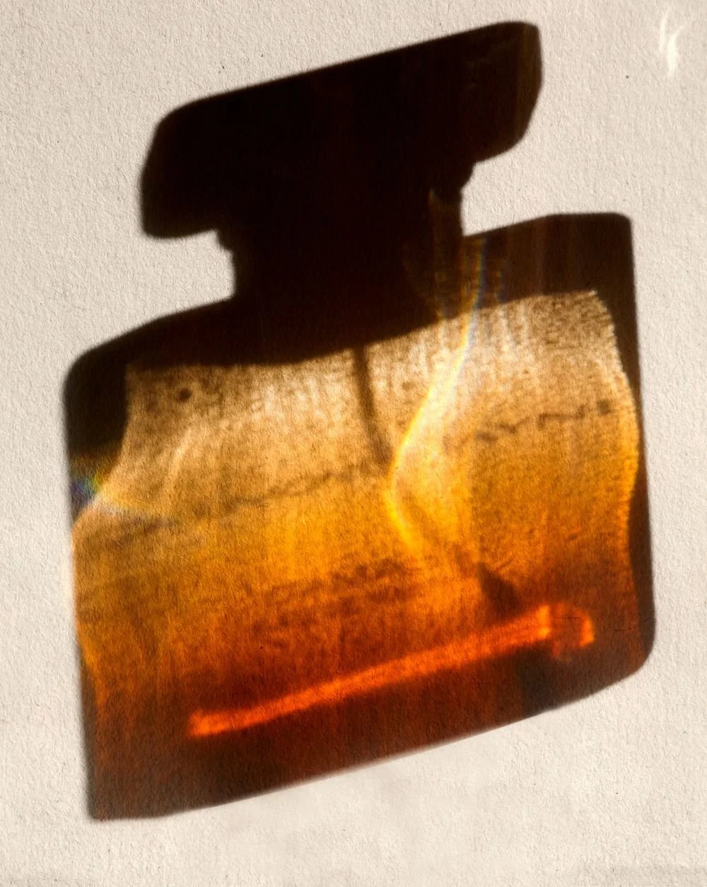 Une projection d'un désert aride avec un éclairage orange et une silhouette de montagne au fond, créée par la lumière passant à travers une tranche de pierre ou de verre coloré.