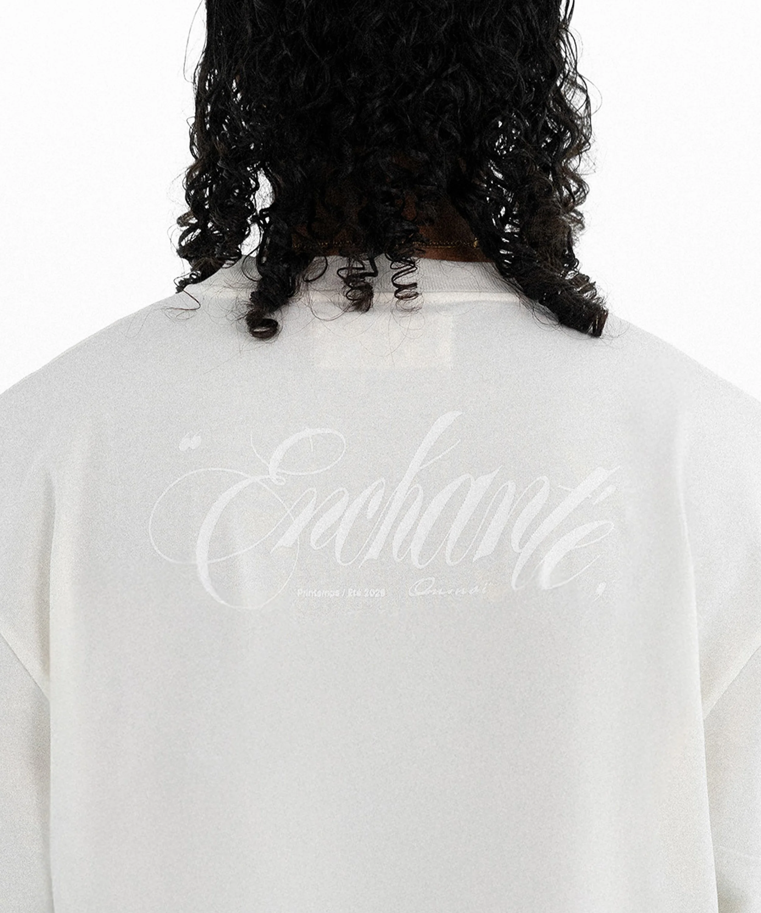 Vue de l'arrière d'une personne portant un t-shirt blanc avec le mot 'épaisseur' écrit en cursive sur le dos.