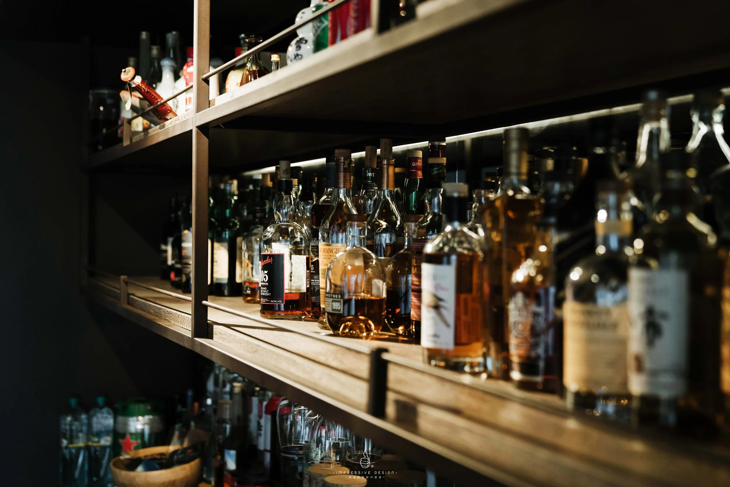 Shelves stocked with assorted bottles of liquor, including whiskey and other spirits, in a dimly lit bar.
