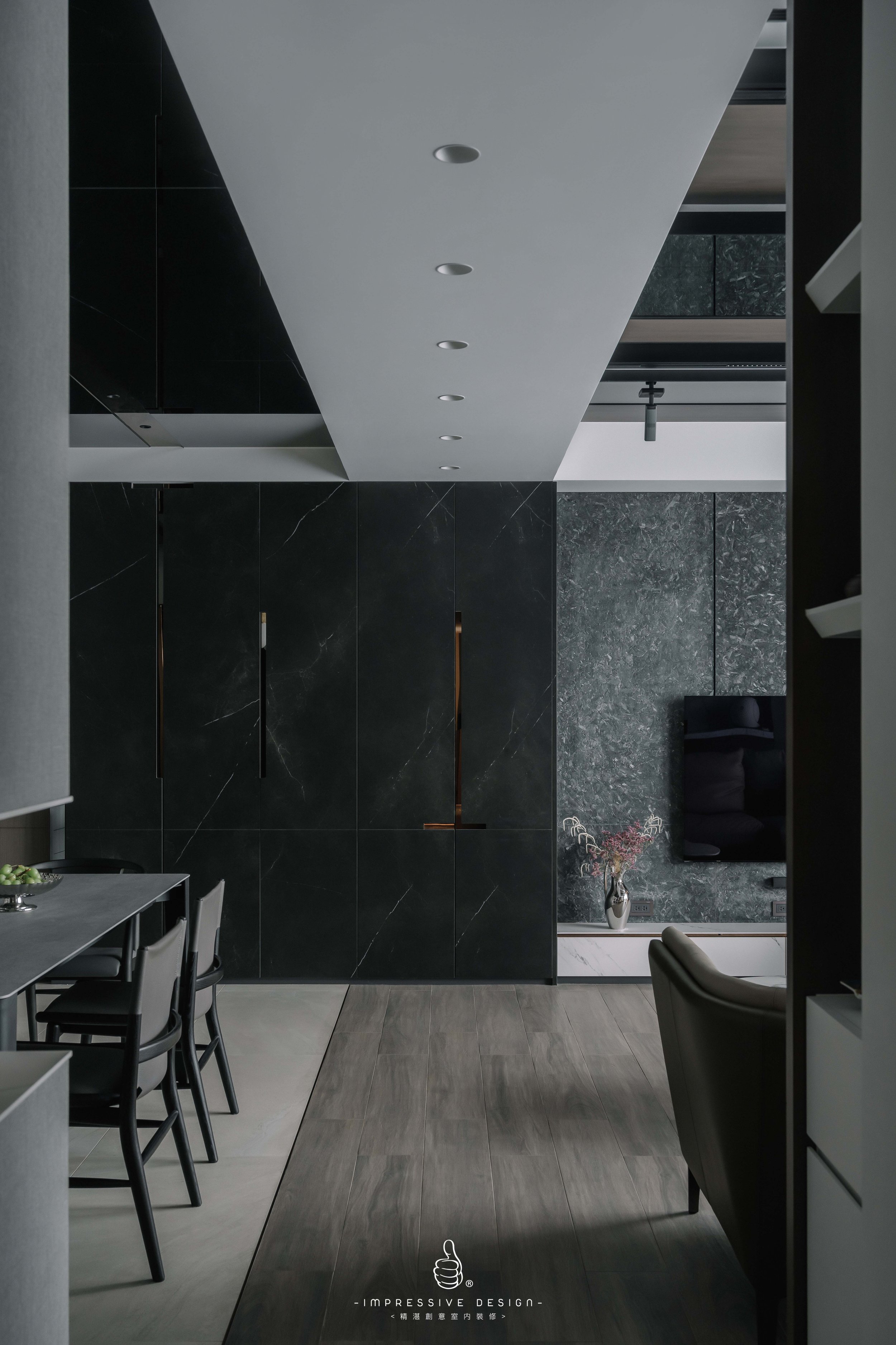 Modern interior living space with dark marble walls, a flat-screen TV, and minimal furniture, featuring a sleek, contemporary design.