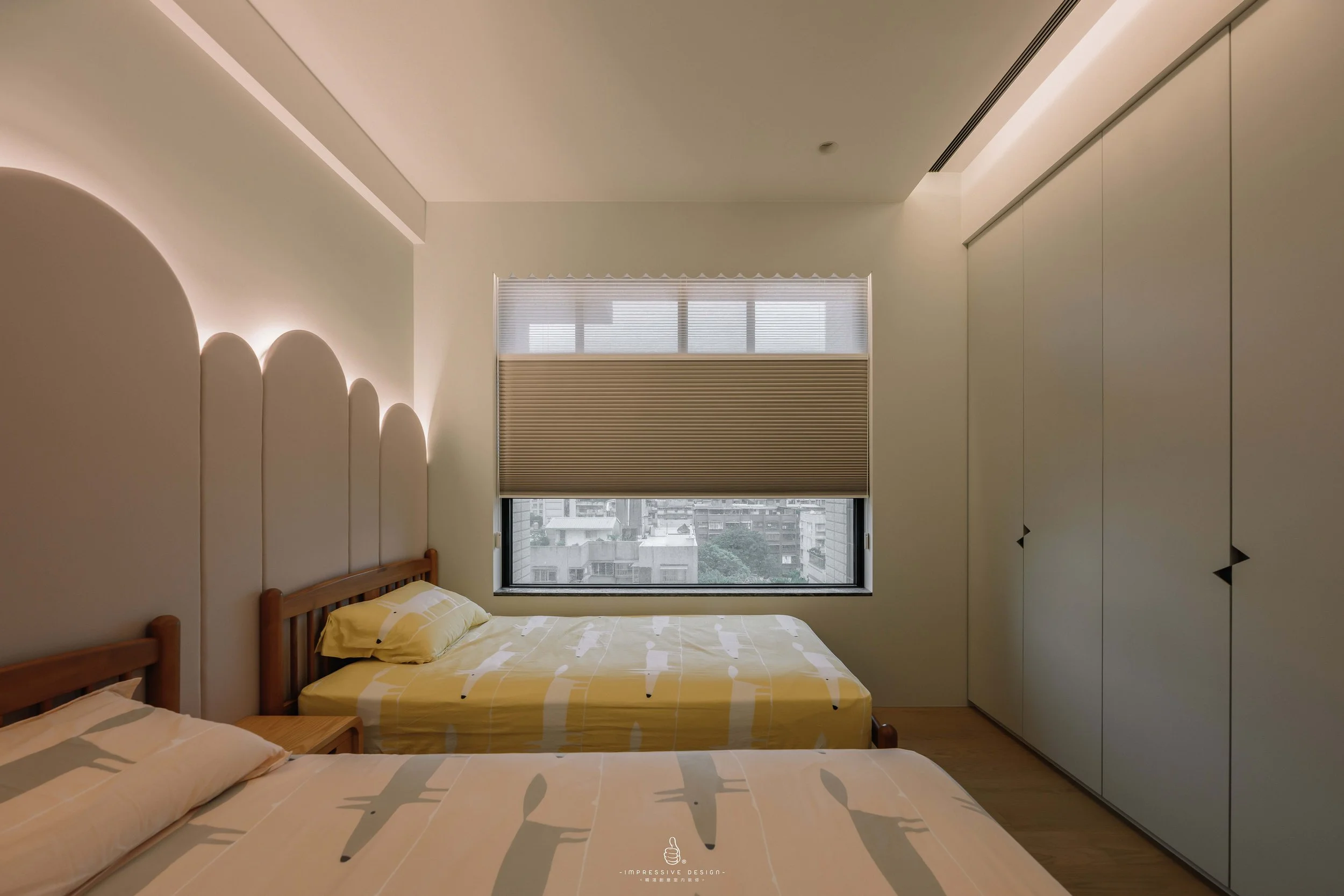 Modern bedroom with two beds, a window with beige blinds, minimalist decor, and a white closet on the right.