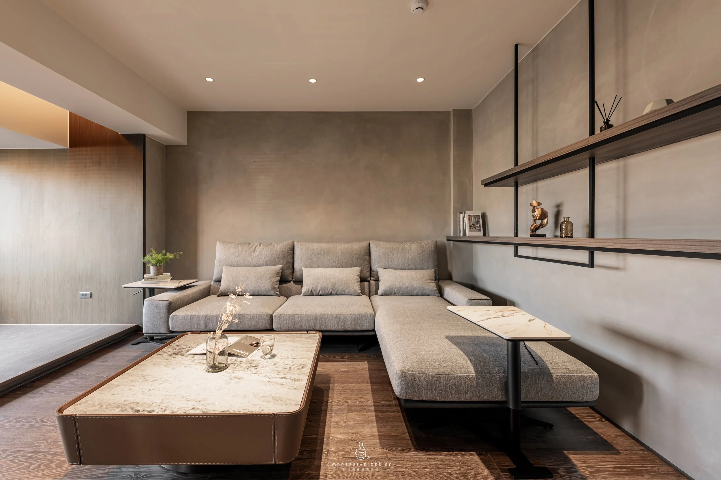 Modern living room with gray sectional sofa, wooden coffee table, and minimalist wall shelf with decor.