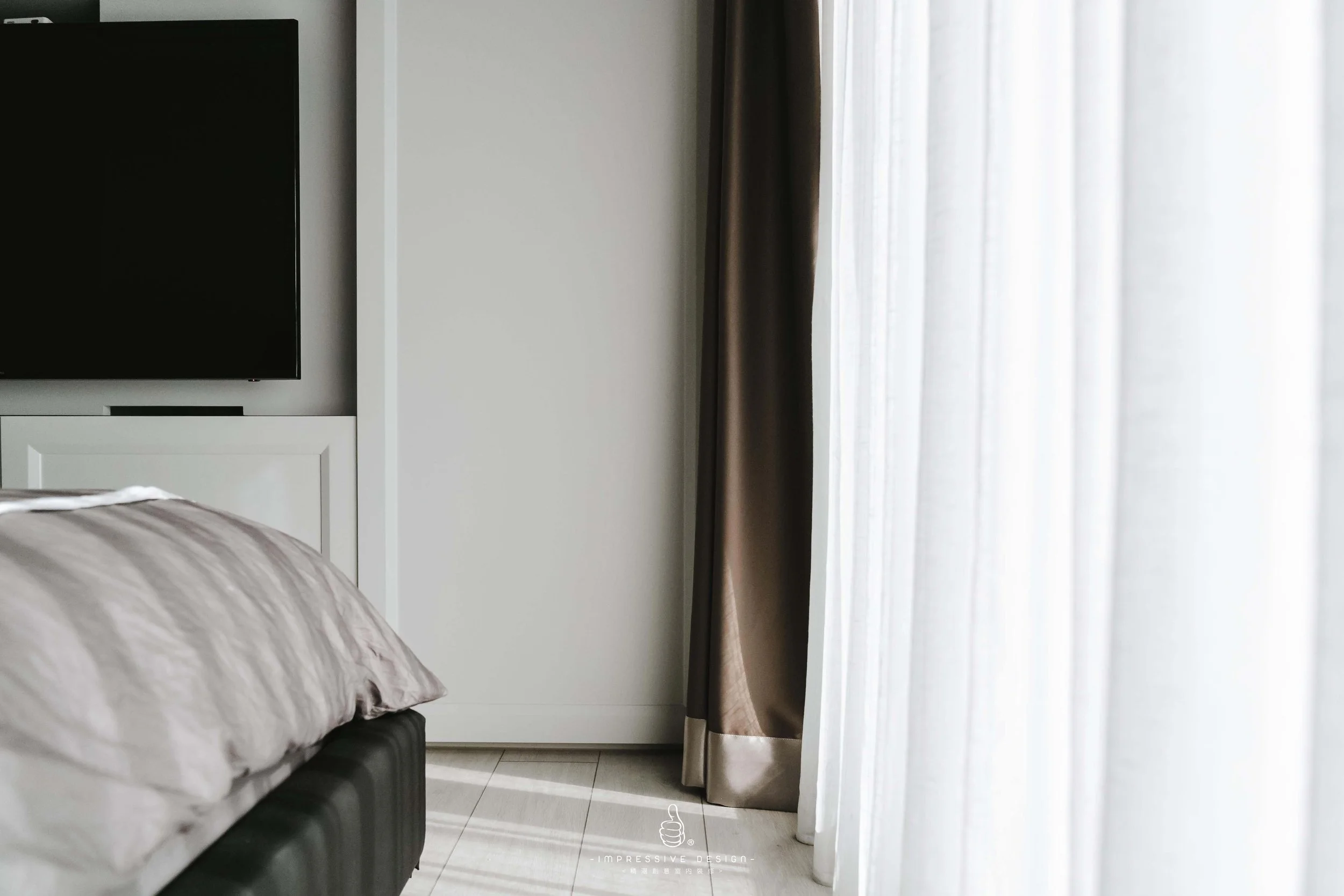 Part of a bedroom with a bed, a flat-screen TV, a white cabinet, a window with curtains, and a tiled floor.
