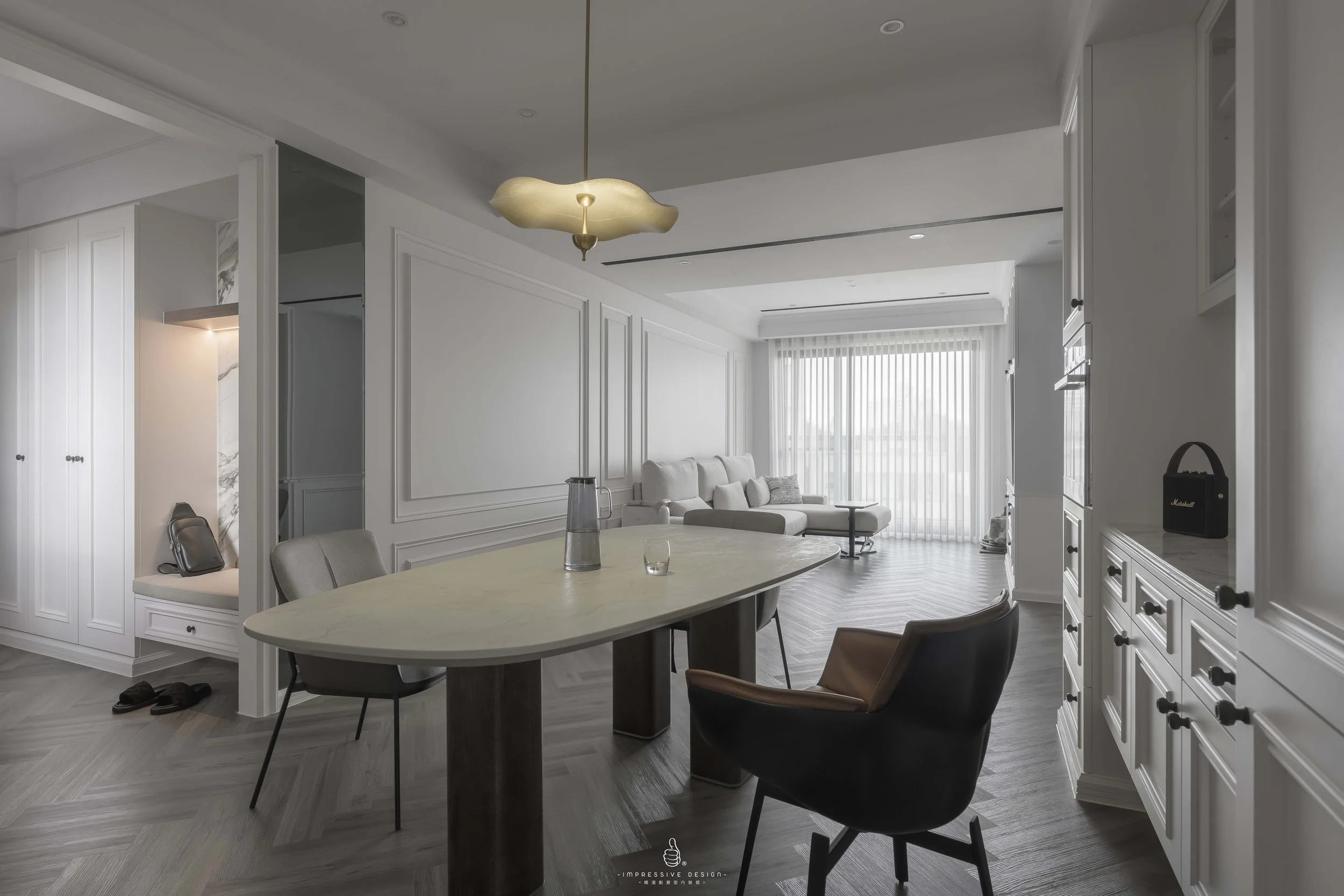 Modern living and dining area with white walls, light-colored flooring, a beige sofa, a round table with chairs, and large windows with vertical blinds.