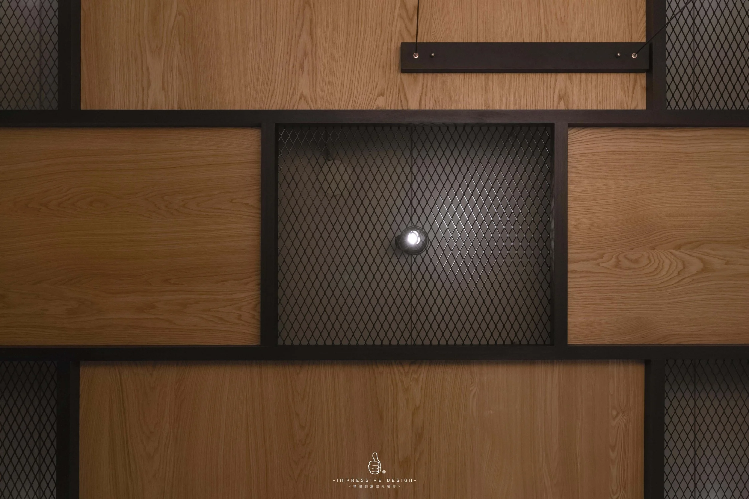 Close-up view of a modern ceiling with wooden and black metal grid panels, and a single light fixture in the center.