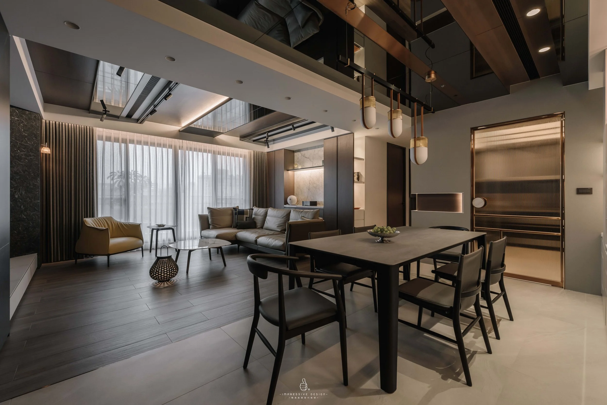 Modern, stylish living room and dining area with large windows, sheer curtains, contemporary furniture, pendant lighting, and a mix of dark and light decor.