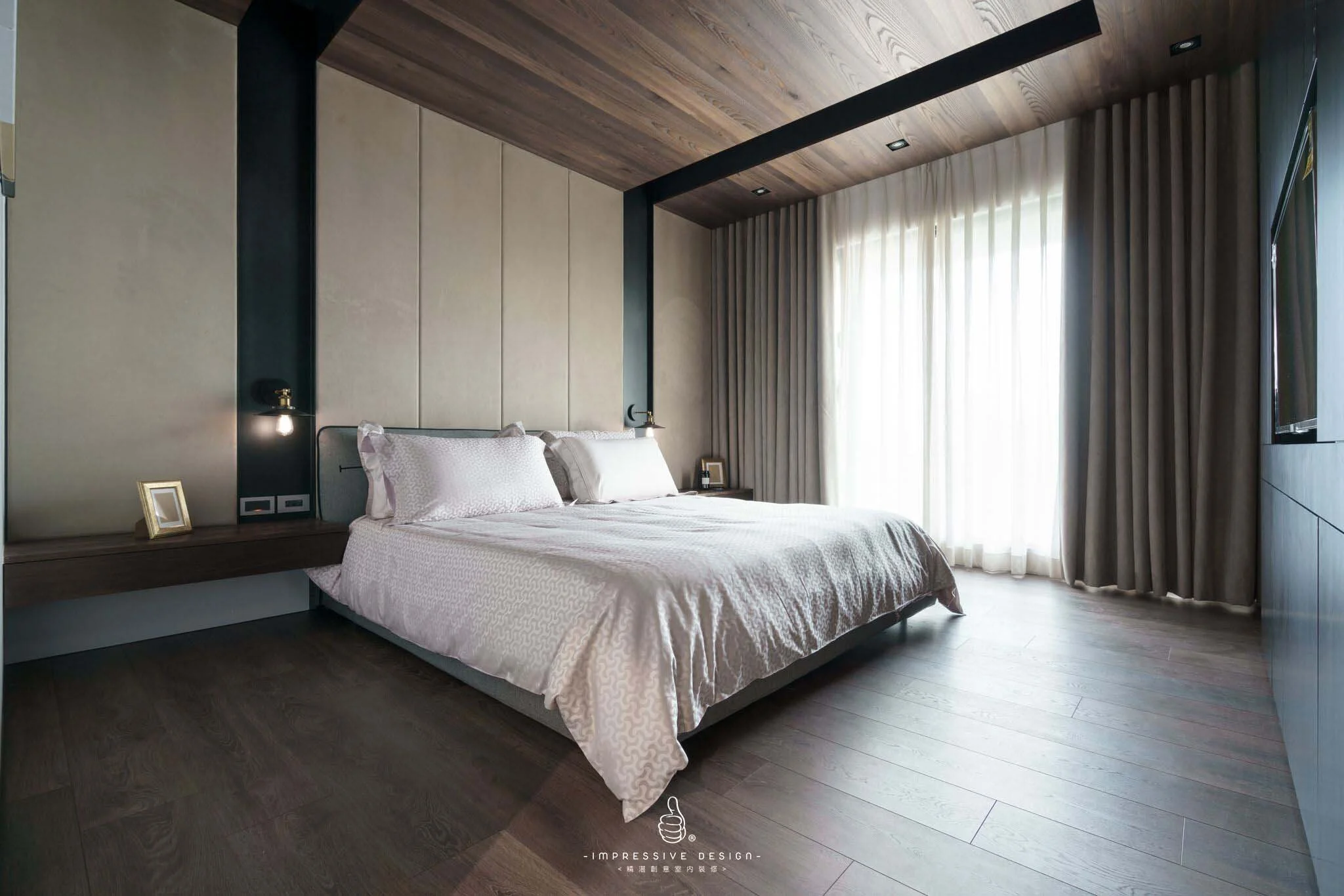 Modern bedroom with a large bed, beige padded headboard, dark wood floating nightstand, framed photo, large window with sheer curtains, and a ceiling with wood paneling.