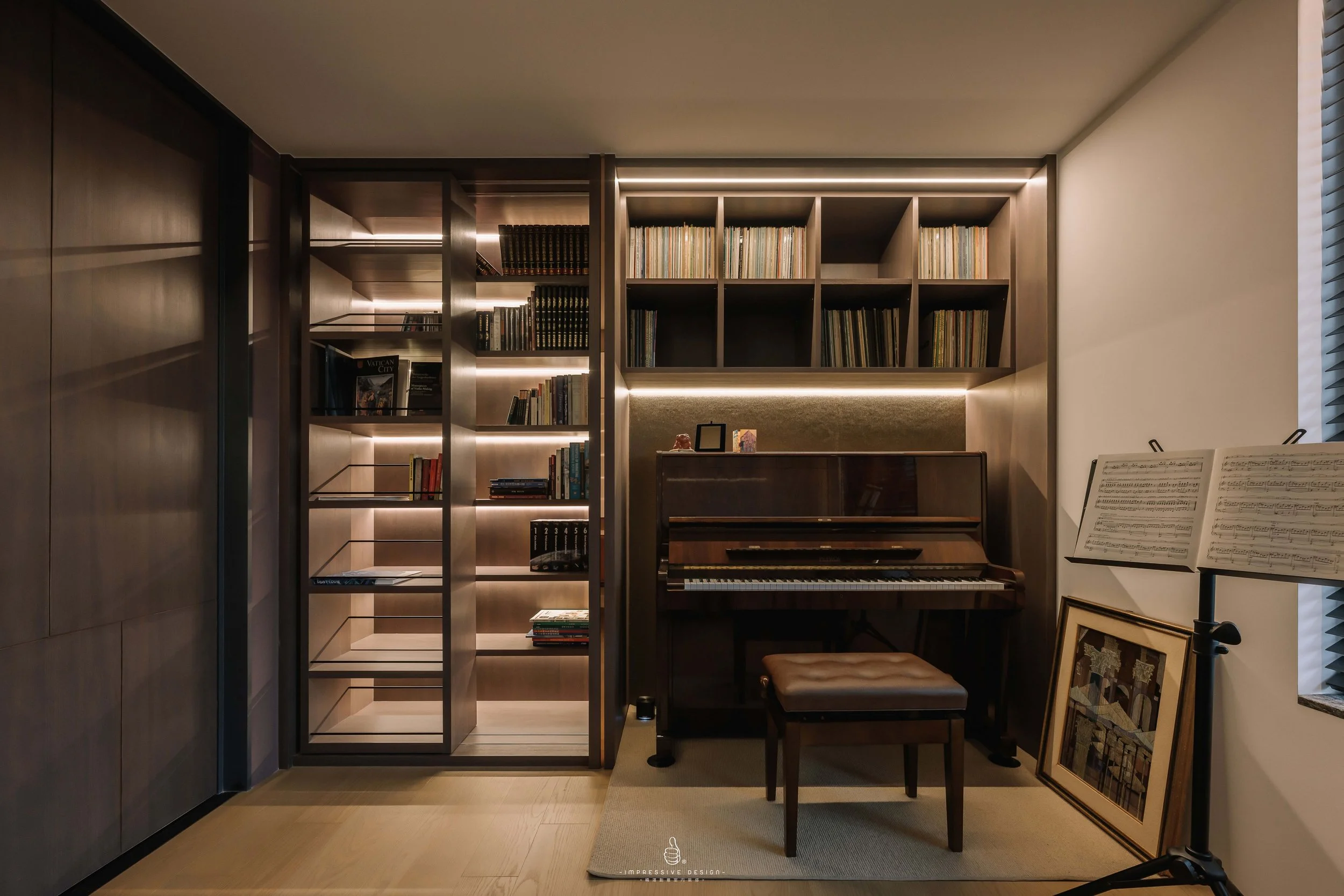 A cozy music room with a vintage upright piano, open sheet music stand, and a cushioned stool. Behind the piano are bookshelves filled with books, giving the space a warm, inviting atmosphere.