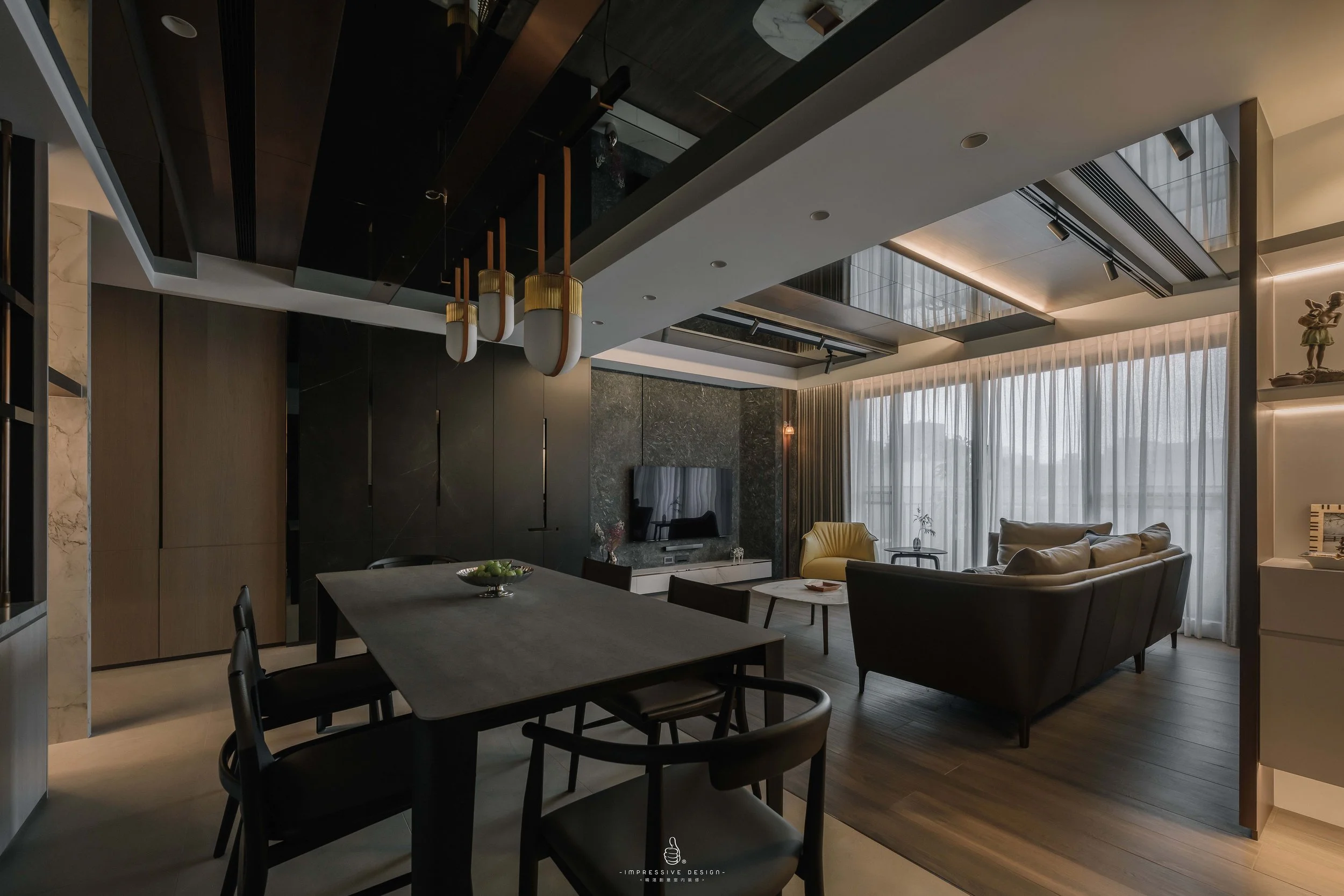 Modern living room with black, white, and beige decor, a dark wood dining table, black chairs, a sofa, large windows with sheer curtains, and ceiling lighting fixtures.