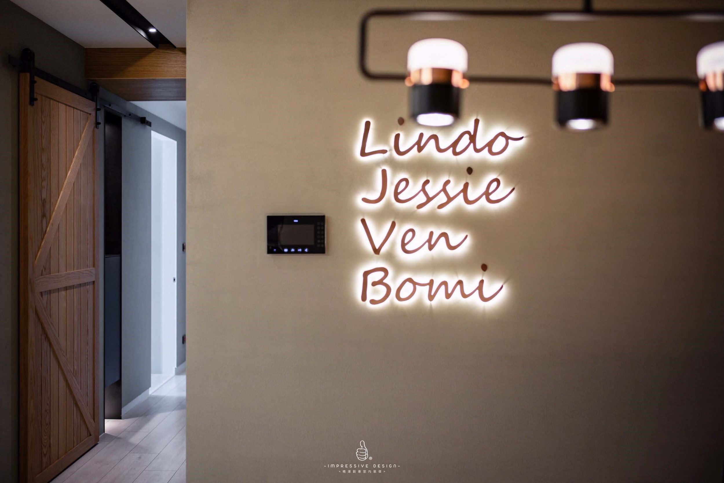 Neon sign on wall reading 'Lindo Jessie Ven Bomi' in a modern interior with wooden sliding door and hallway.