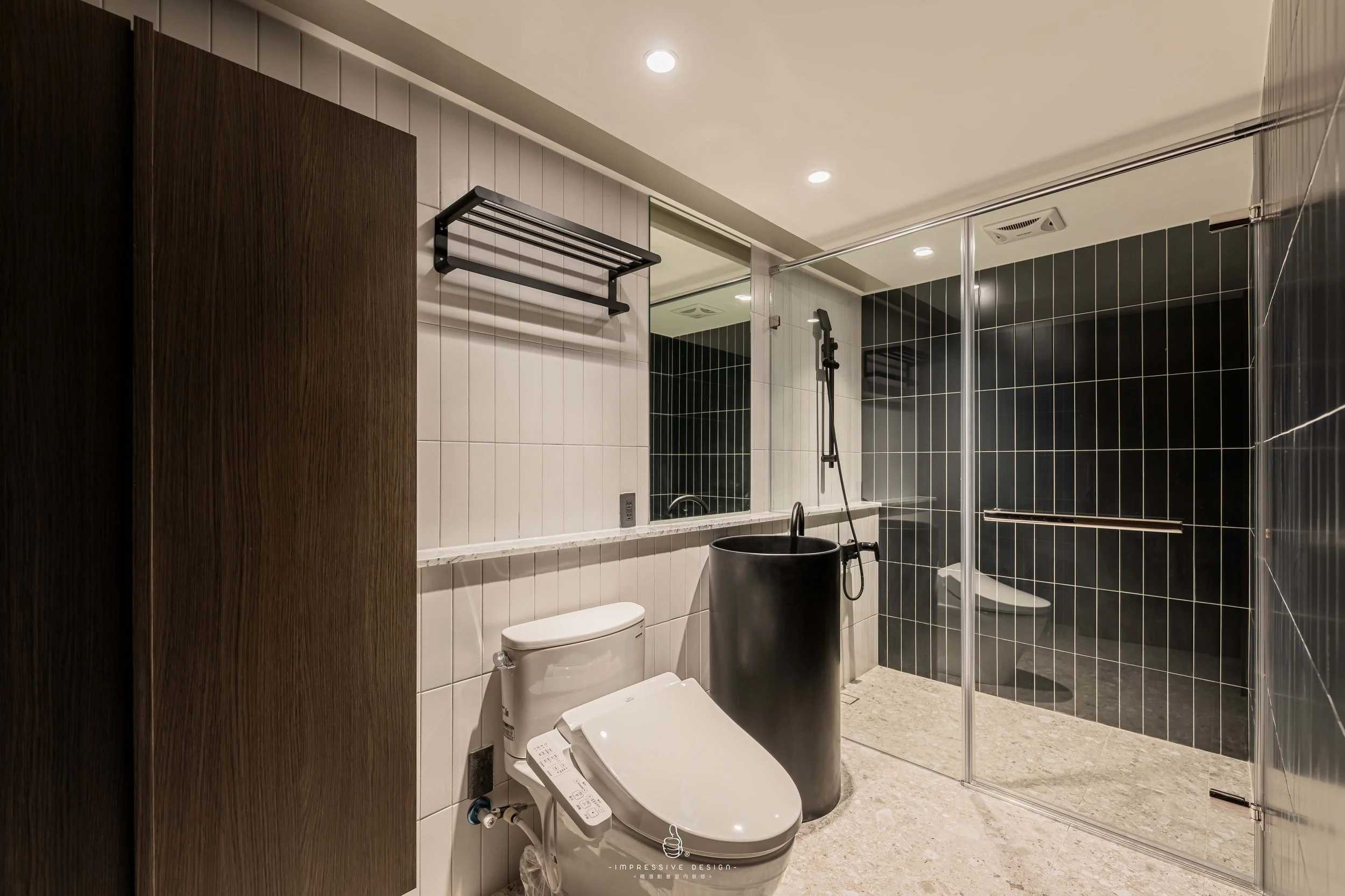 Modern bathroom with black and white tiles, a white toilet, a black freestanding tub, and a glass shower enclosure.