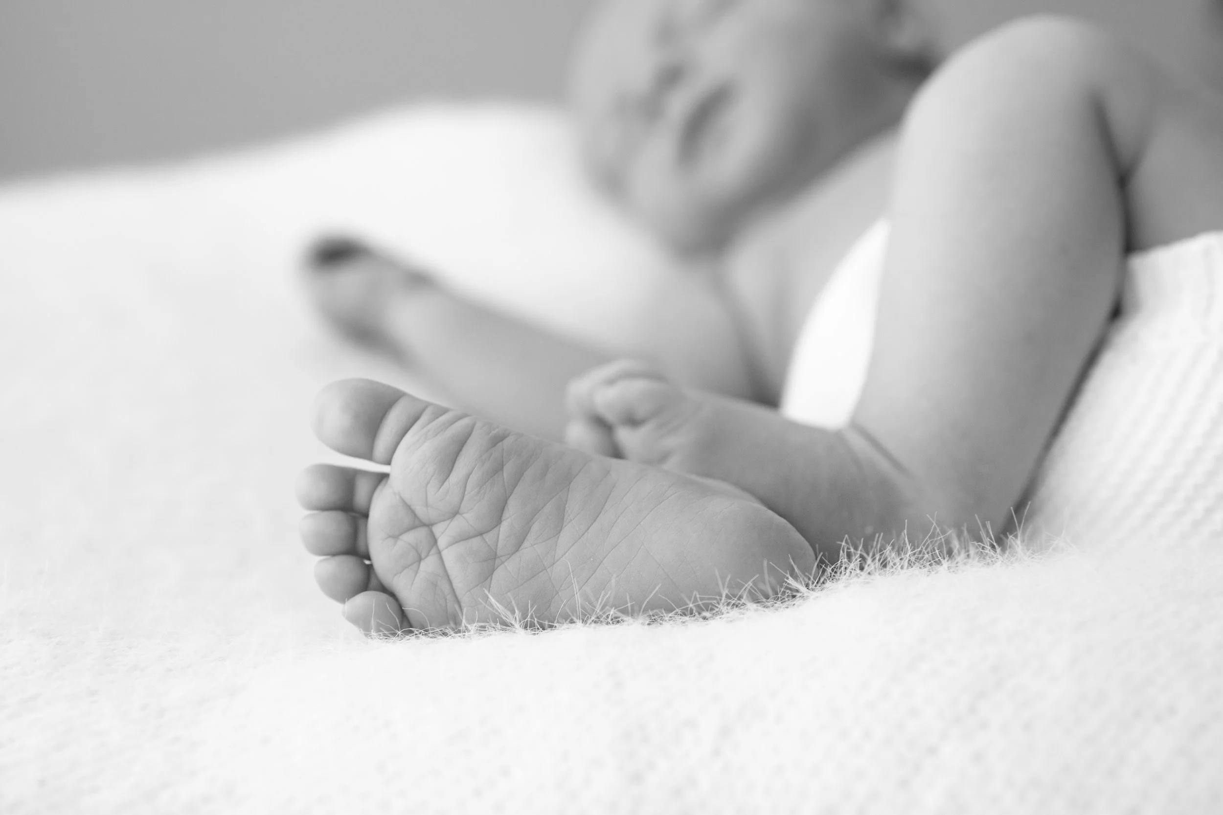 A beautiful black and white artistic photograph of newborn baby feet by Michelle Gaskell, used for the Sleepy Mums Newborn Masterclass.