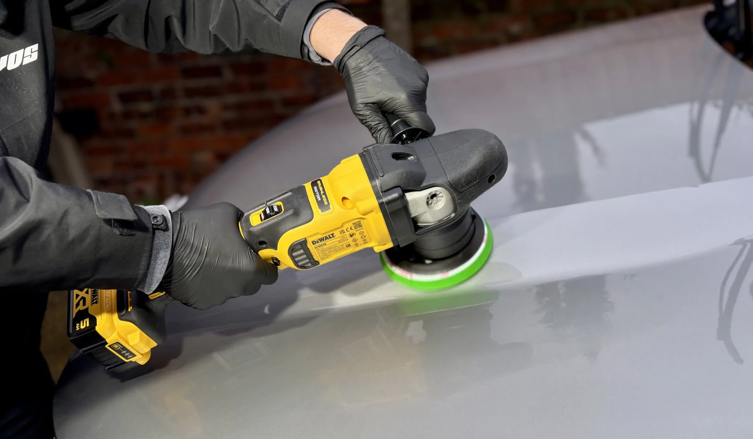 Polishing a black vehicle with machine polisher