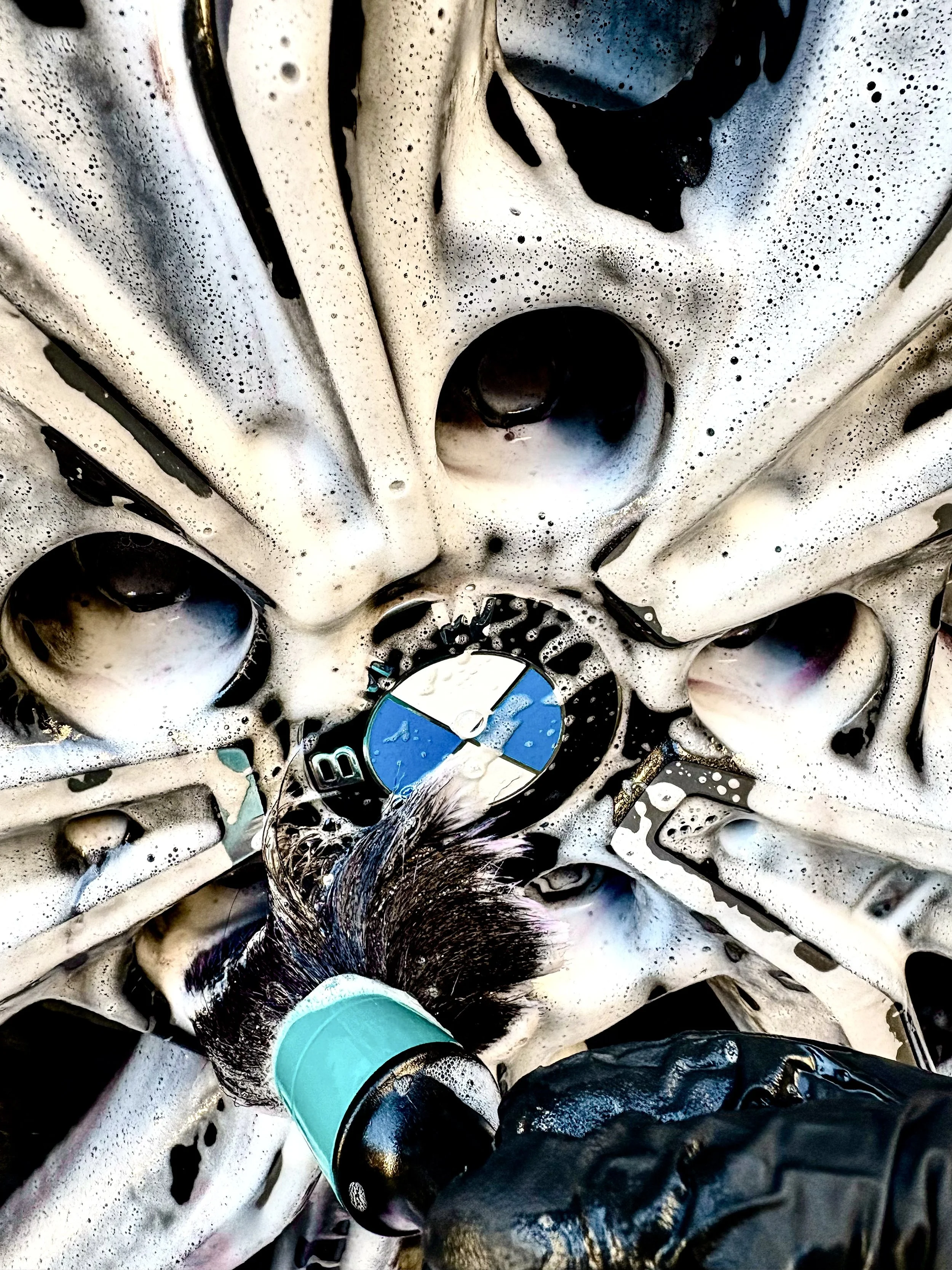 Close up cleaning a BMW alloy wheel with a feather tipped brush