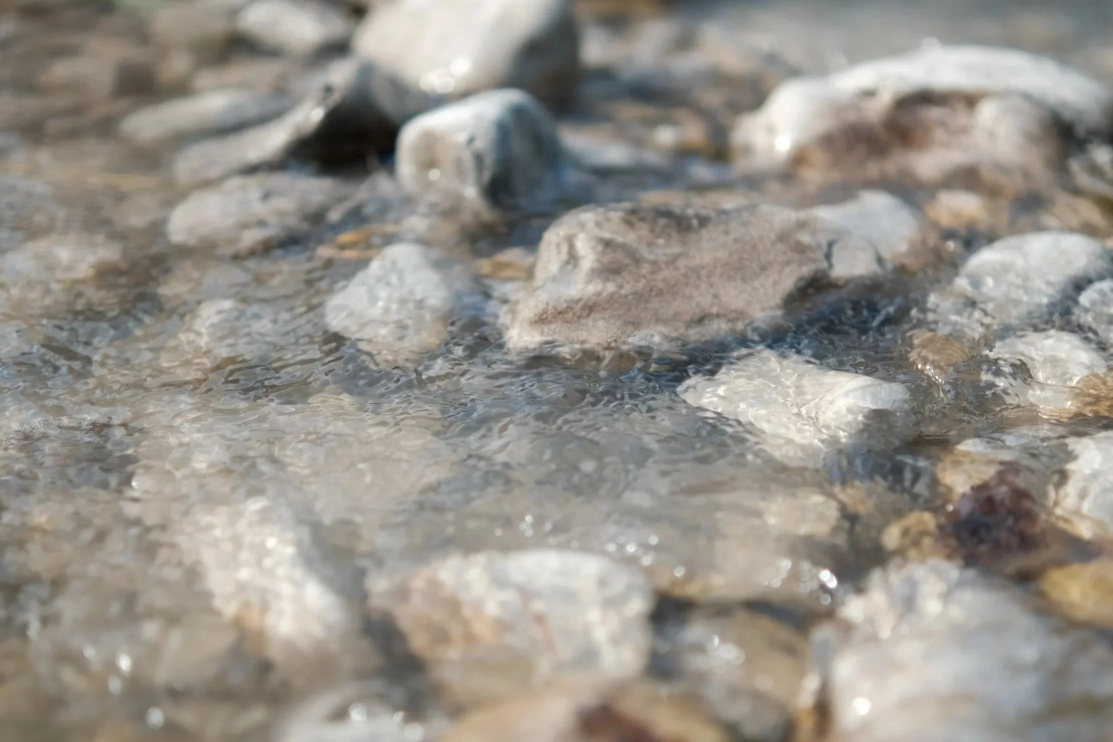 Close-up of water flowing over rocks in a shallow stream or river. outdoor product photography children's fashion brand photographer childrenswear clothing