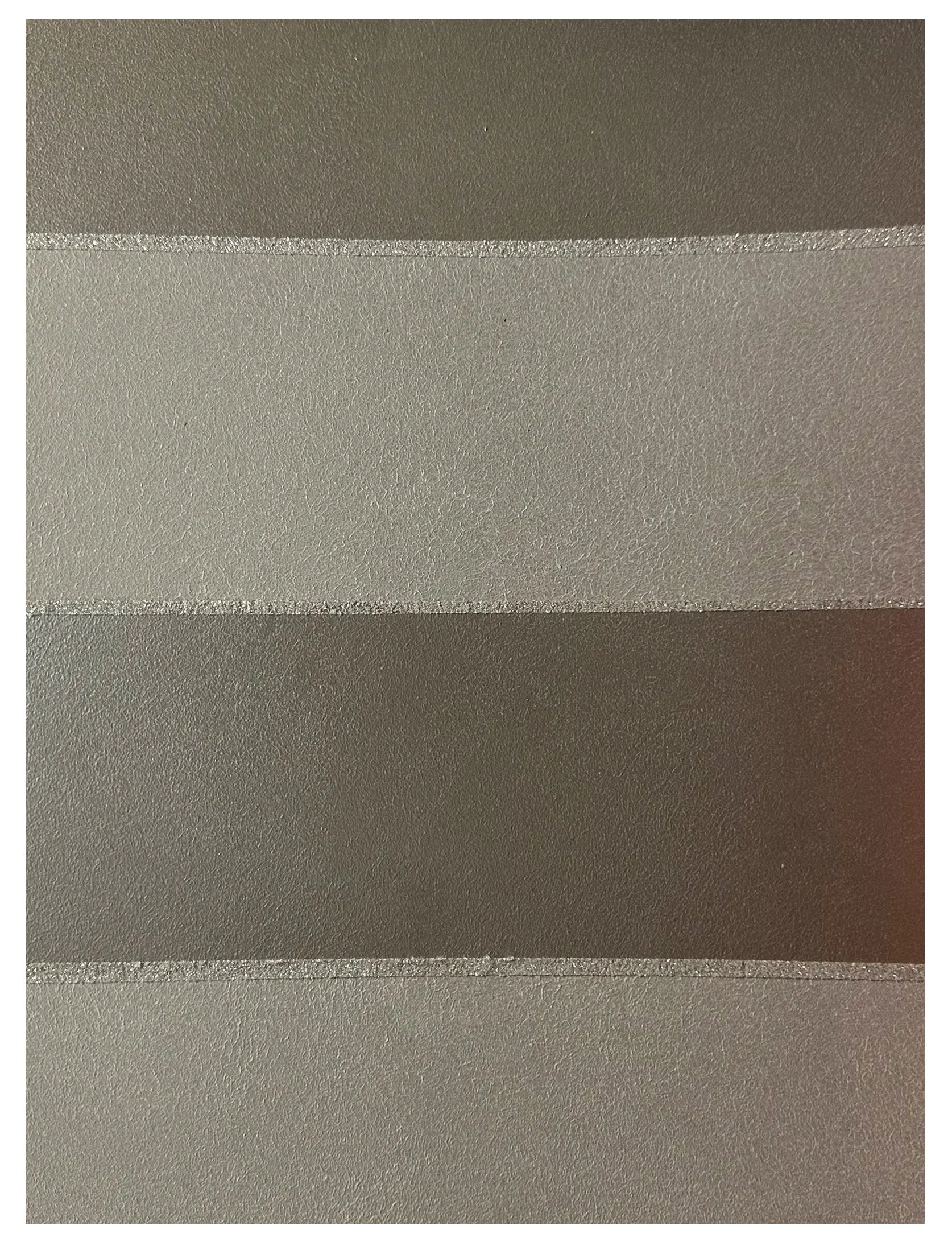 Close-up of a surface with horizontal metallic silver and dark gray stripes, textured with small bumps.