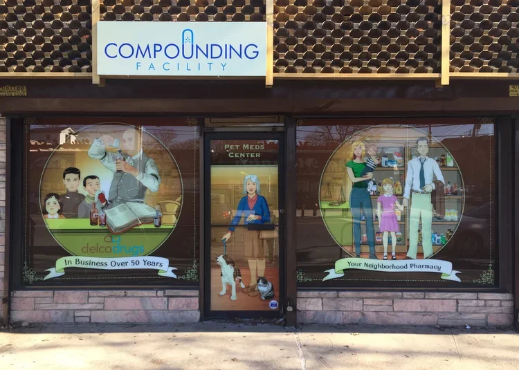Illustrated storefront for a compounding pharmacy with window graphics depicting a pharmacist, customers, and pets, and signs indicating over 50 years in business and neighborhood pharmacy.