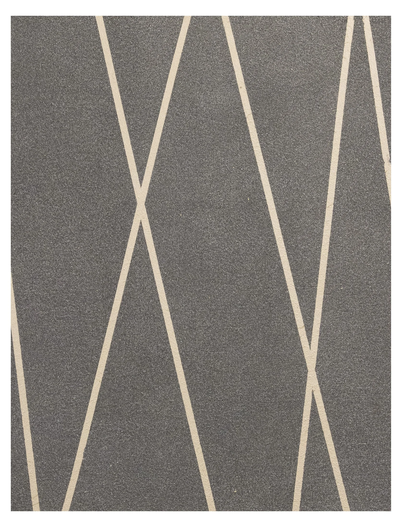 Close-up of a textured dark gray surface with intersecting beige lines creating a geometric pattern.