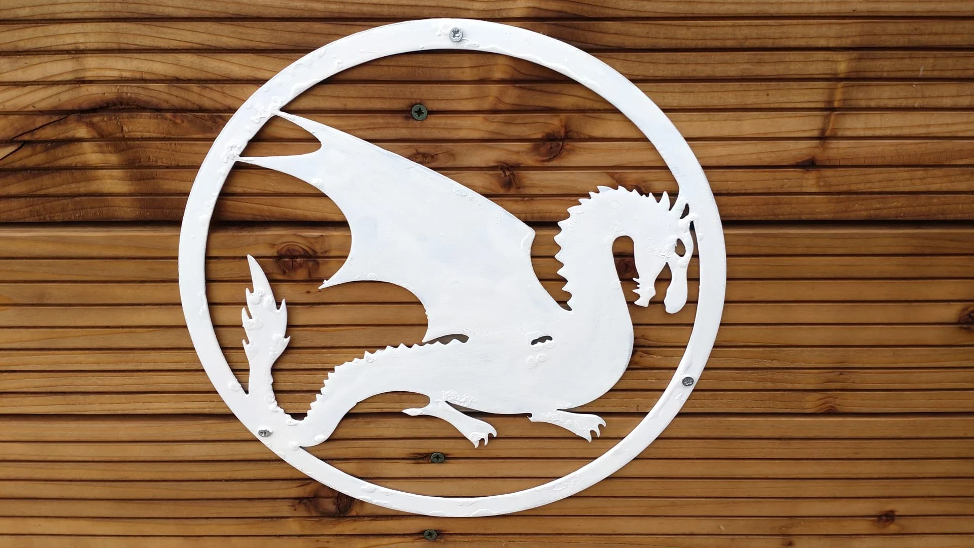 White circular logo of a dragon inside a circle mounted on a wooden wall.