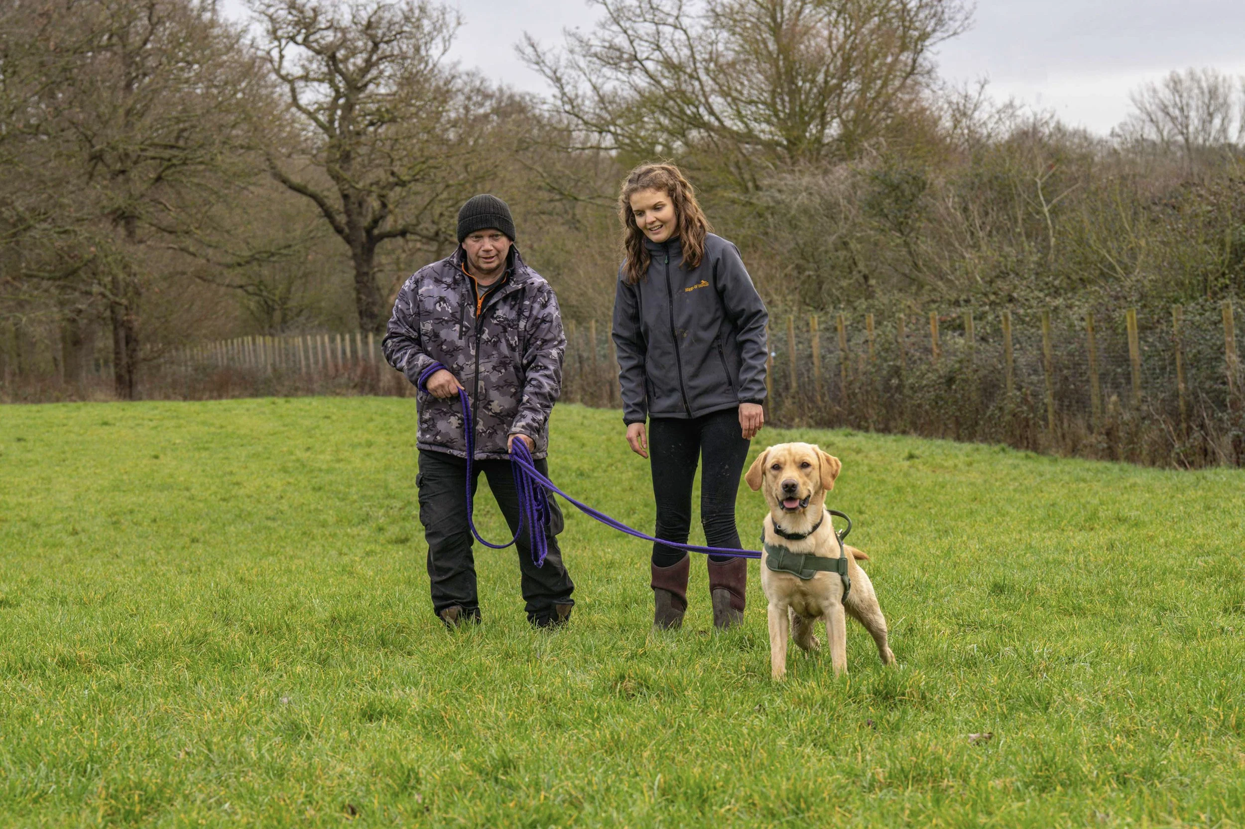 Two people with a dog. The dog has a loose lead.