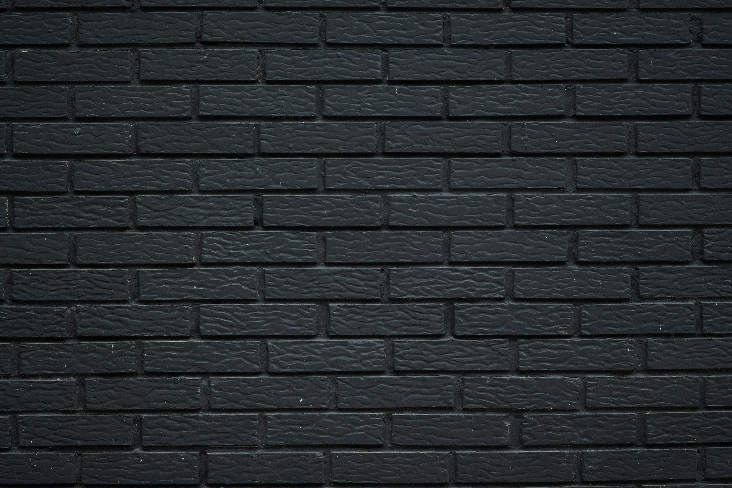 Close-up of a black brick wall with textured bricks.