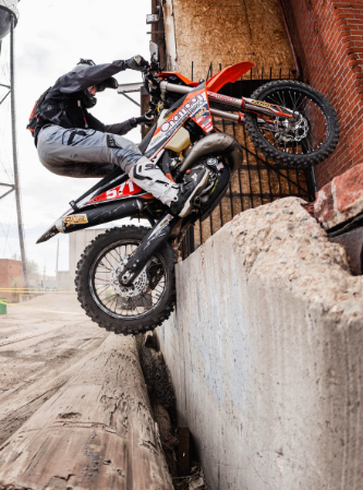 Motorcycle rider attempting to climb over a concrete barrier on an off-road dirt track